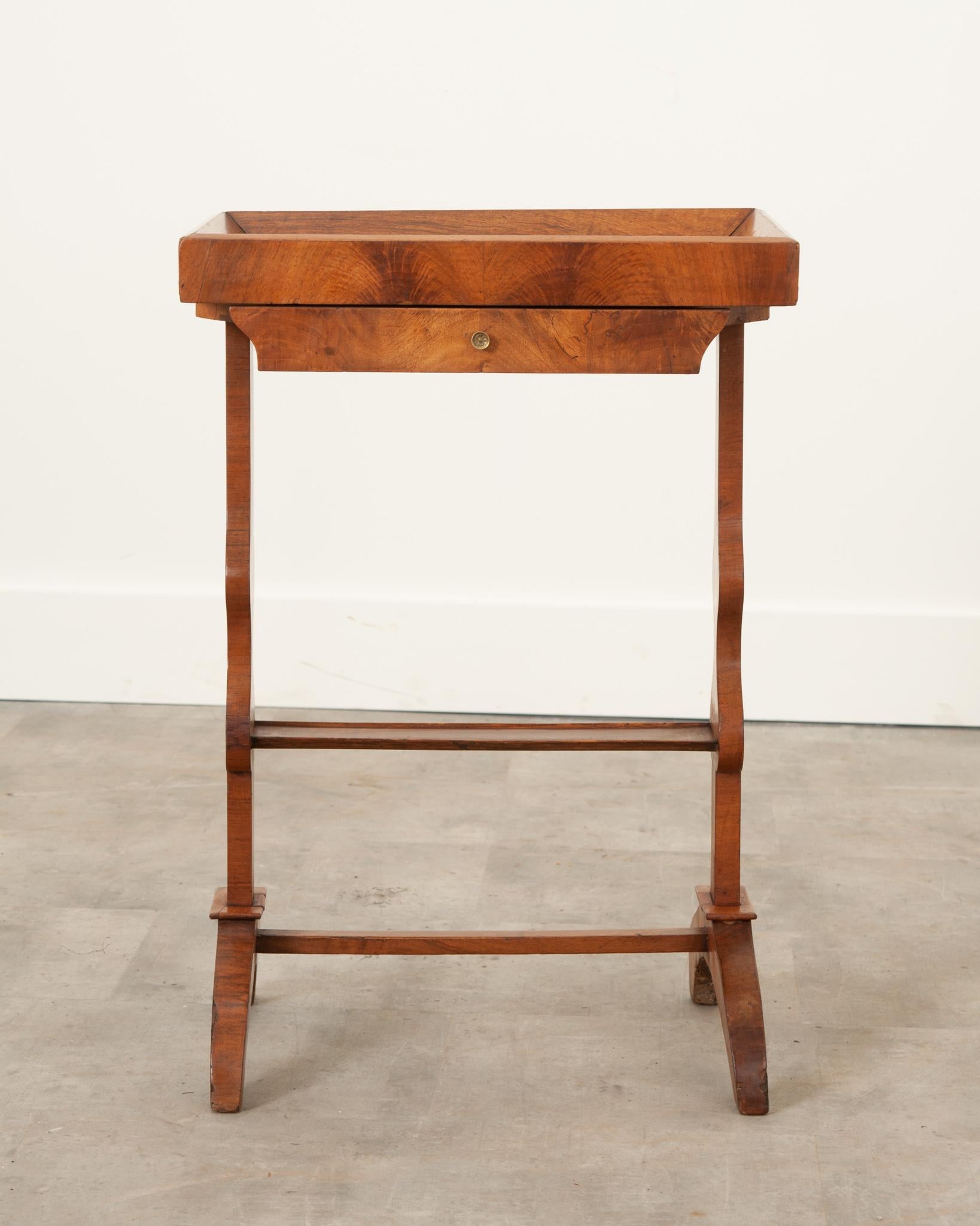 A delightful solid walnut accent table from 19th Century France. Incredible expression can be found in the grain throughout the carefully selected walnut. The rectangular table top has a beveled frame extending above the top’s surface, giving the