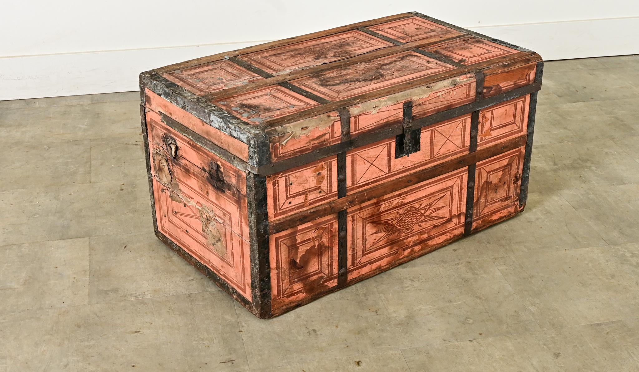 A fantastic 19th century French traveling trunk, constructed of pine and steel, dressed in light peach colored illustrations on paper. Graphic, geometric patterns and stylized cartouche animate the exterior, the gridded layout underscored by the