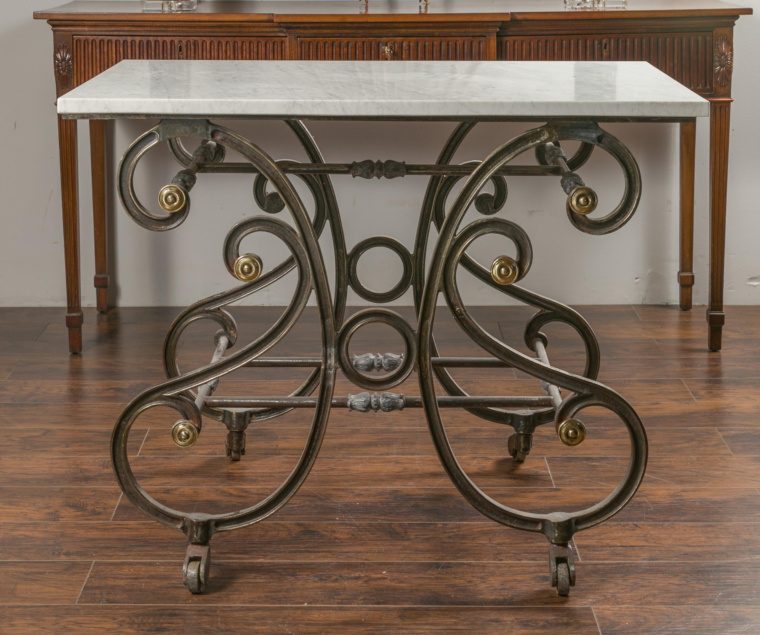 A French steel baker's table from the 19th century, with white marble top, brass accents and casters. Created in France during the 19th century, this baker's table features a white veined marble top sitting above a scrolling steel base accented with