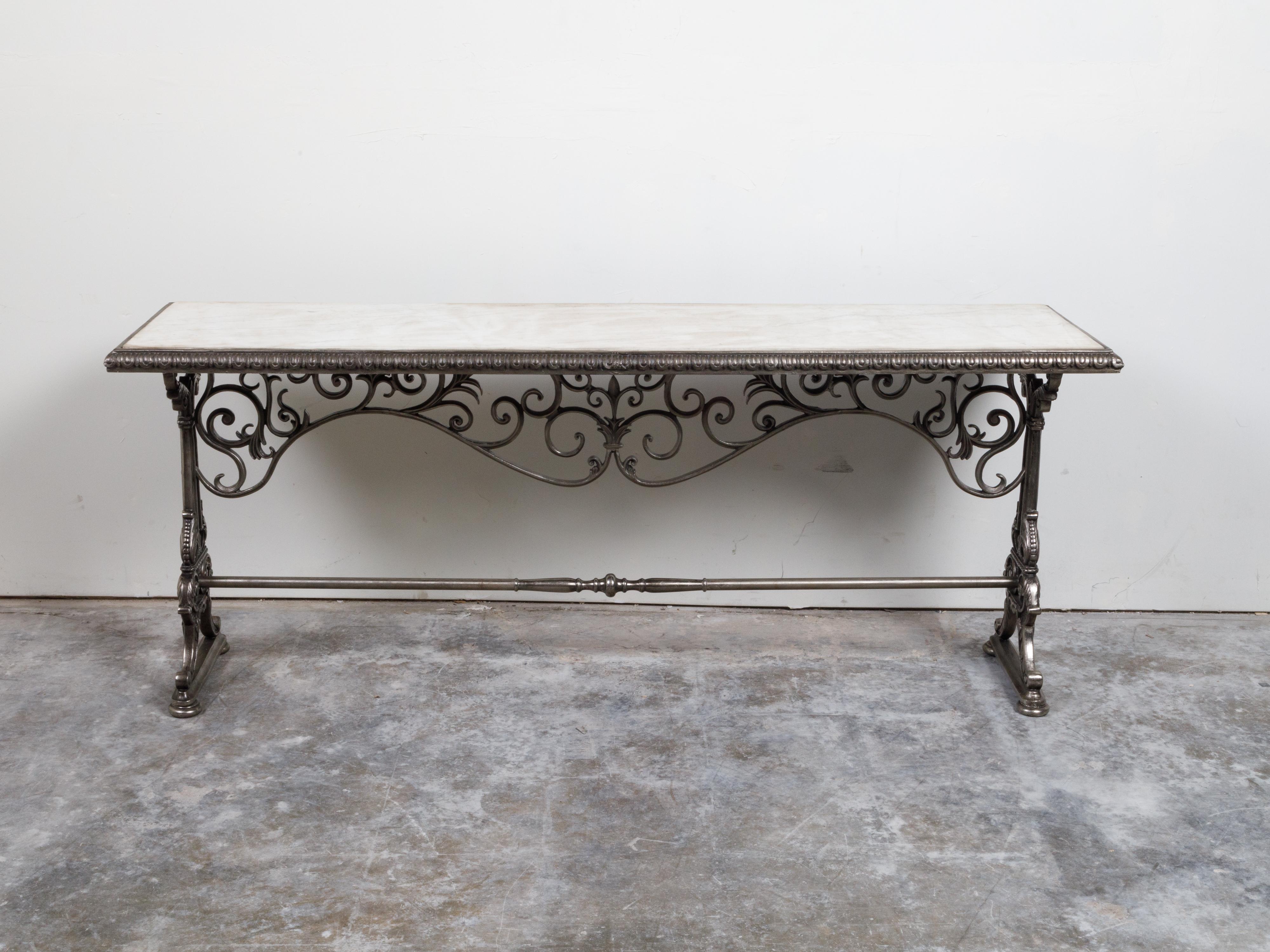 A French steel pastry table from the 19th century, with white marble top and scrolling accents. Created in France during the 19th century, this pastry table features a rectangular white marble top surrounded by an egg-and-dart edge. Raised on an