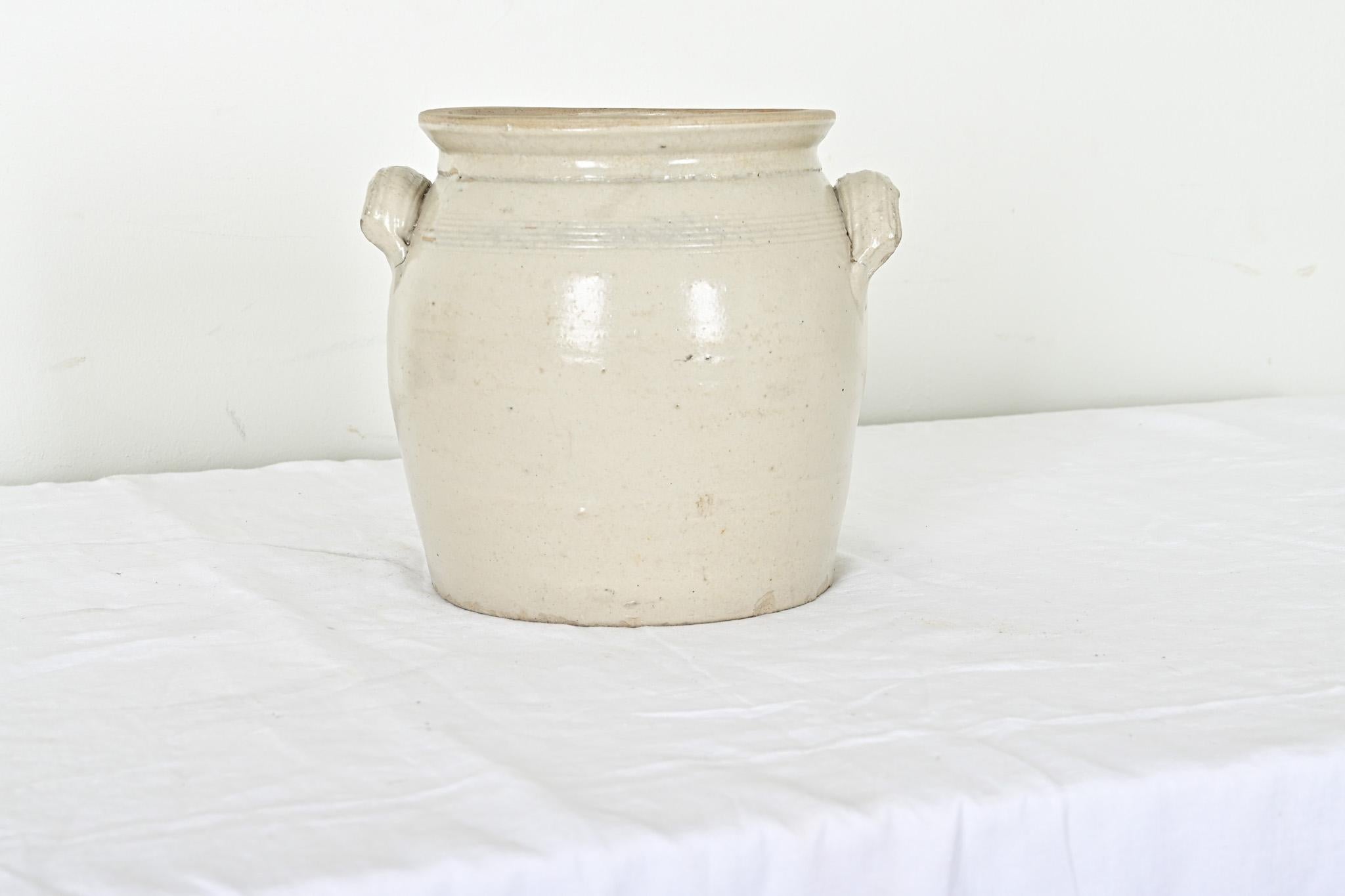 French Provincial 19th century ecru-glazed stoneware two-handled crock or storage jar. This charming vessel would bring farmhouse authenticity to the modern kitchen by its rustic form and handmade construction with combed, decorative rings around