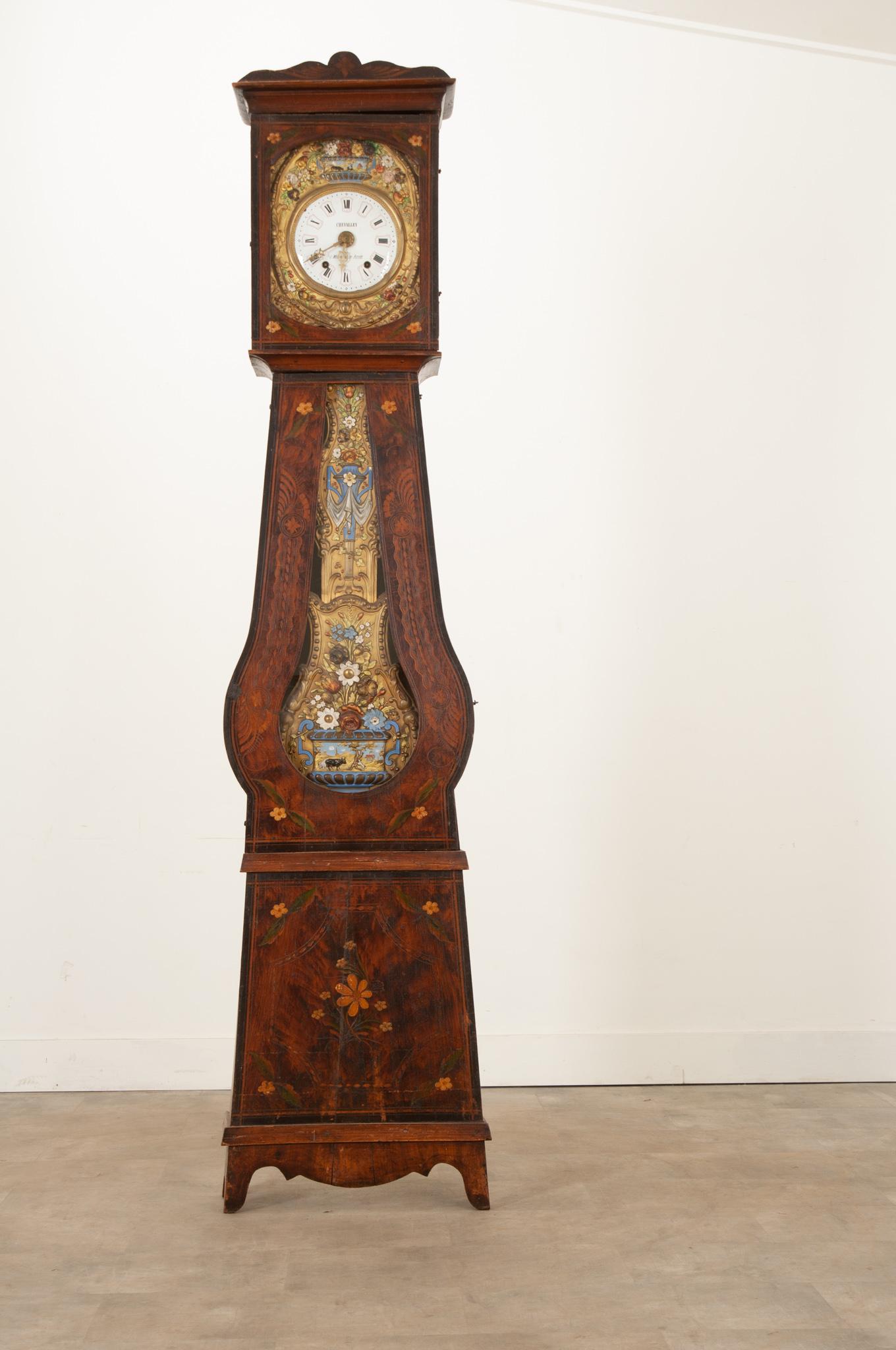 This French 19th century banjo shaped case clock is an eye catching piece in any space. Topped by an ornately carved cornice above the dial faced door. Supported by an intricate brass repousse frontage, the dial face displays hand painted roman