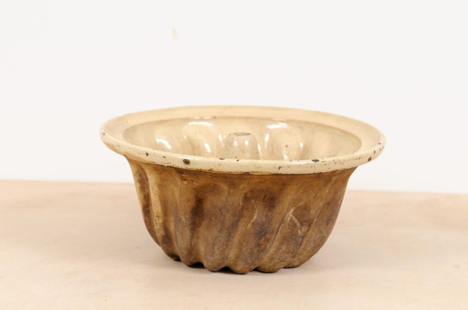 A French terracotta Kouglof cake mold from the 19th century, with beige and brown tones. Created in France during the 19th century, this Kouglof mold will make for a great addition to any kitchen. Boasting a nicely weathered patina, this Kouglof