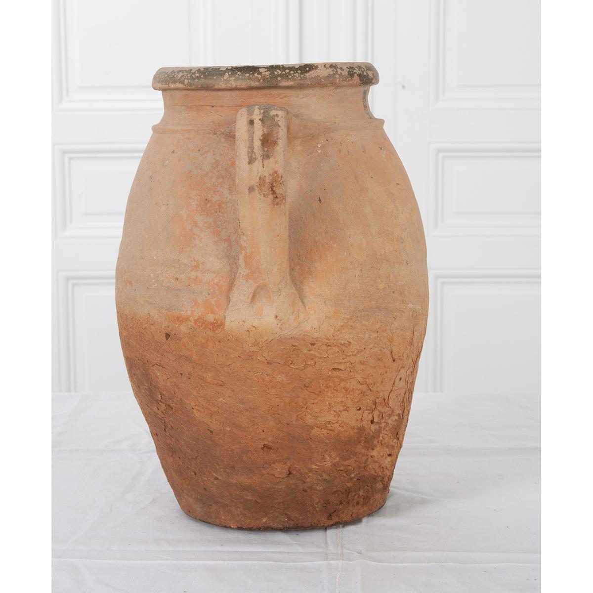 A 19th century terracotta olive jar from France. Its looped handles make lifting the pot a little easier, and the subtle banding found above them, around the lip, gives it a distinct style. While they lend themselves to the kitchen, these charming