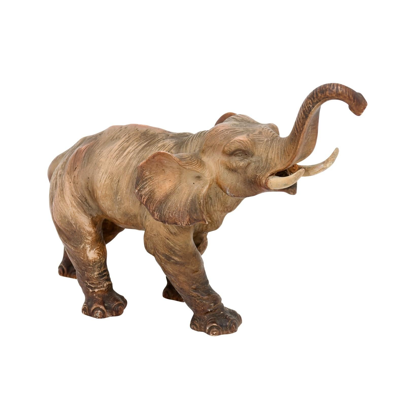 A small French terracotta sculpture from the 19th century depicting a walking elephant with trunk raised, tusks and great expression. Created in France during the 19th century, this small terracotta sculpture captures our attention with its very