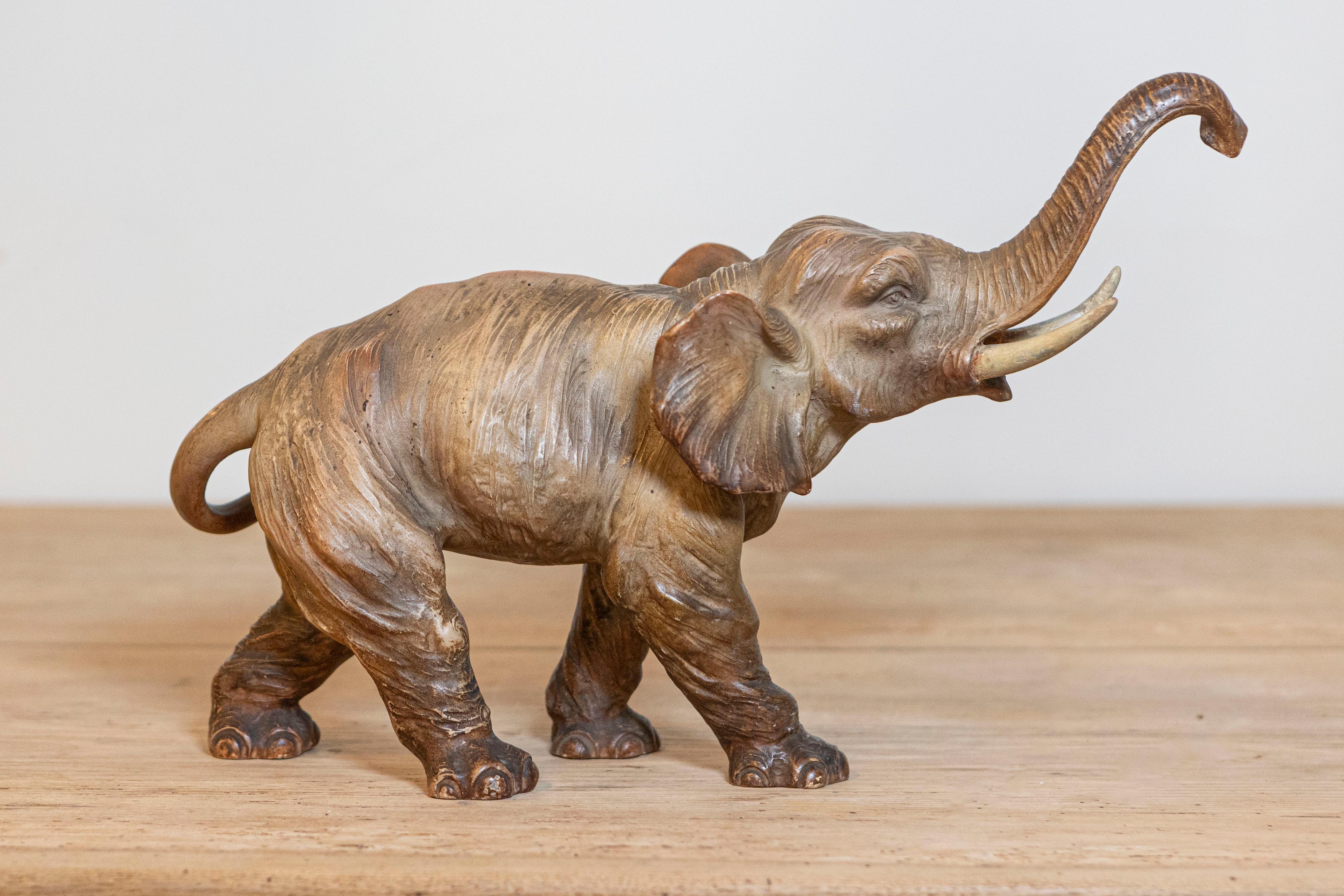 A small French terracotta sculpture from the 19th century depicting a walking elephant with trunk raised, tusks and great expression. Created in France during the 19th century, this small terracotta sculpture captures our attention with its very
