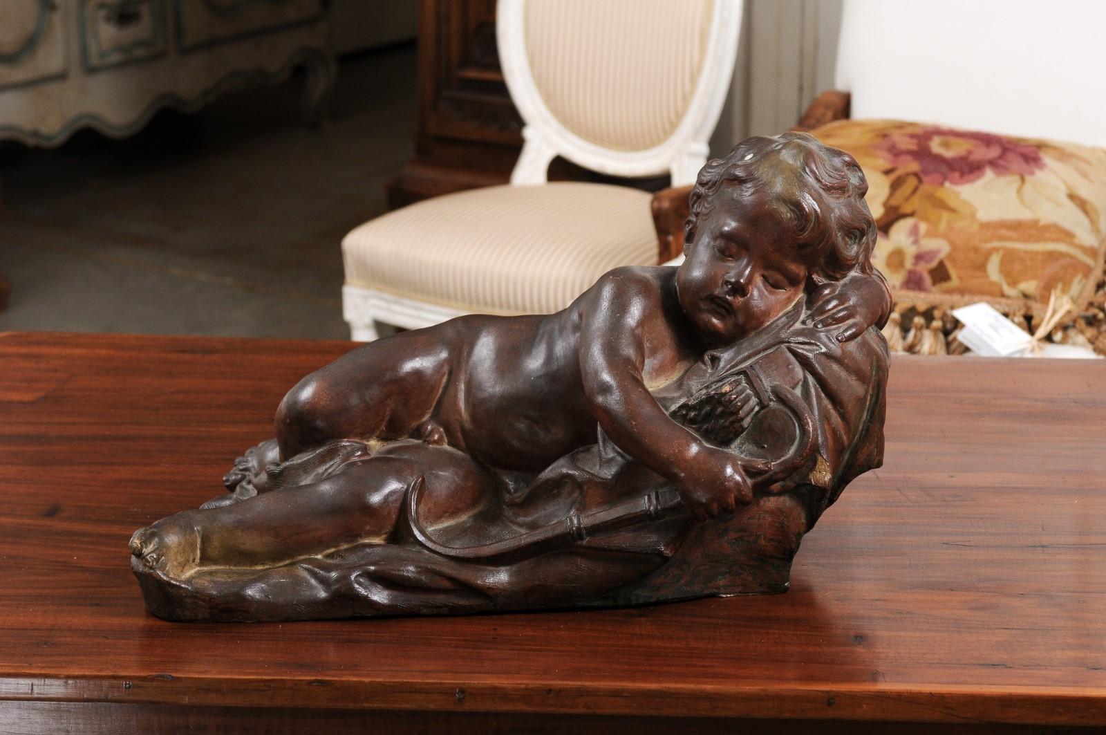 A French terracotta figure of a sleeping cupid from the 19th century, with bow, quiver and arrows, after Italian sculptor Giovacchino Fortini. Created in France during the 19th century, this terracotta sculpture charms us with its depiction of a