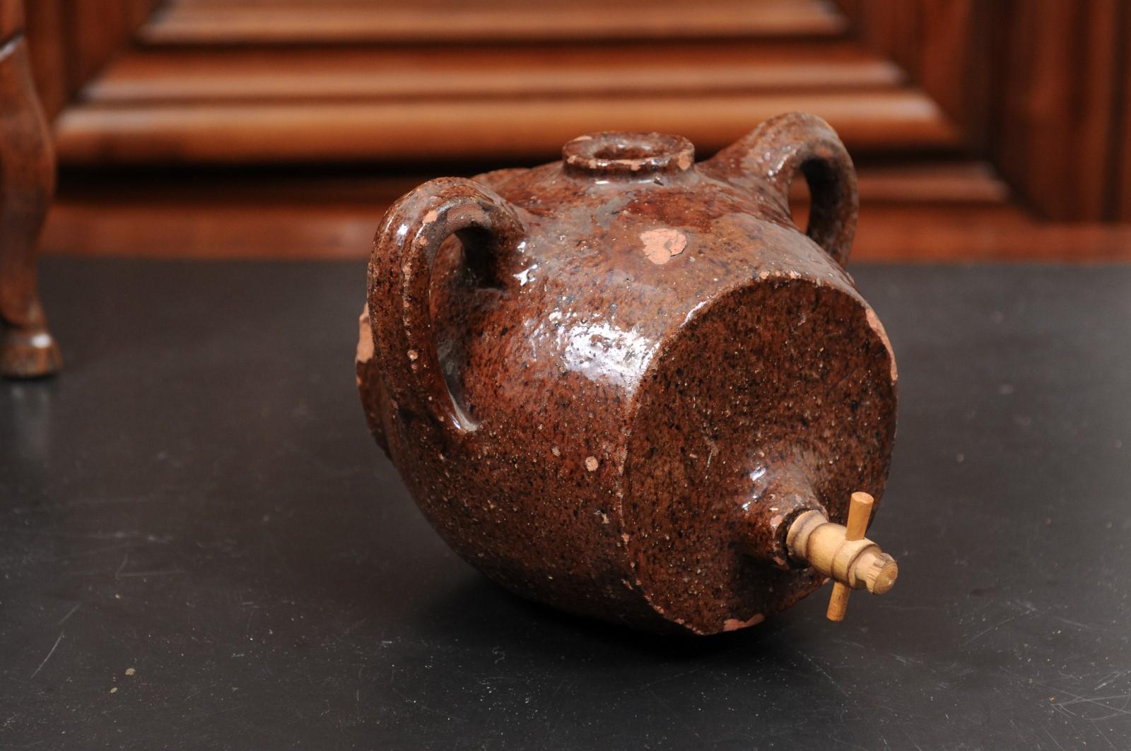 A French terracotta vinegar pot from the 19th century, with chocolate glaze and nicely worn appearance. Created in France during the 19th century, this terracotta vinegar pot charms us with its chocolate glaze and aged patina. Flanked with handles