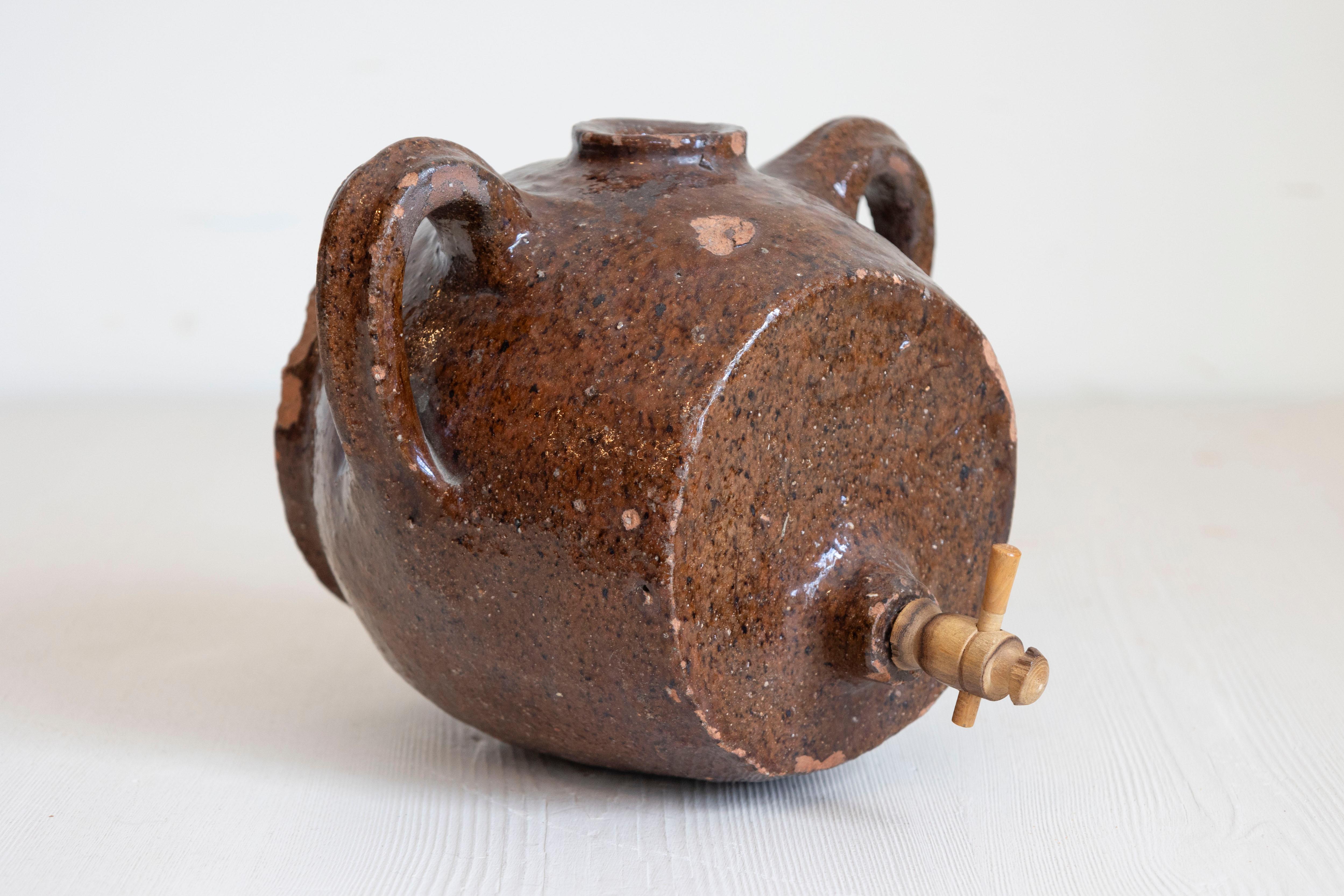 A French terracotta vinegar pot from the 19th century, with chocolate glaze and nicely worn appearance. Created in France during the 19th century, this terracotta vinegar pot charms us with its chocolate glaze and aged patina. Flanked with handles