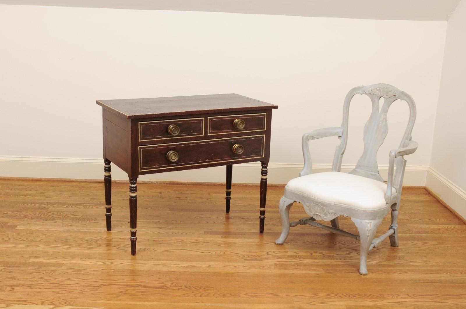 A French three-drawer commode from the 19th century, with cylindrical legs. Created in France during the 19th century, this wooden commode features a rectangular top sitting above three drawers (two small ones over a larger one), each fitted with