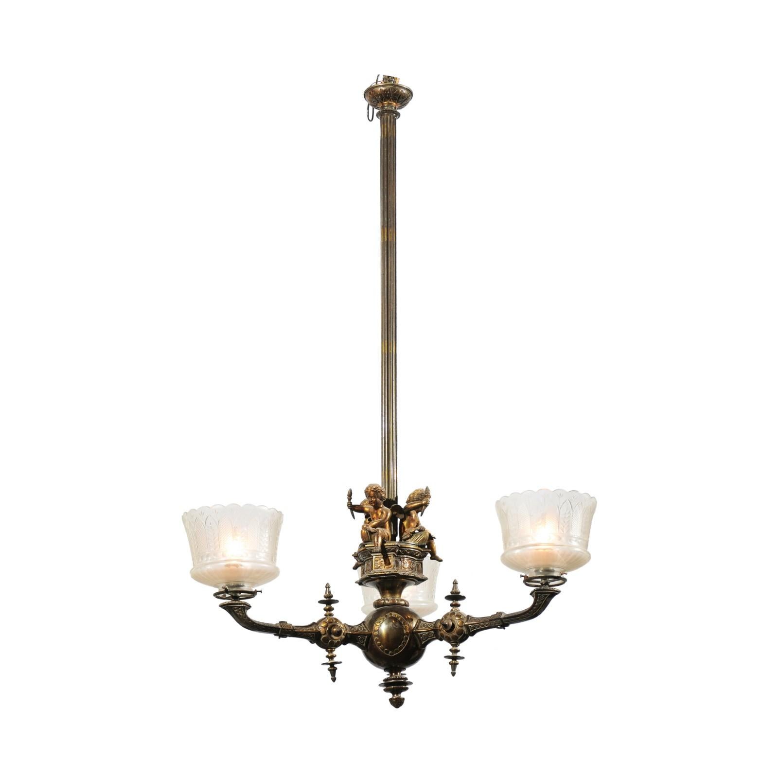 A French three-light bronze chandelier from the 19th century, with cherubs holding torches and Baccarat crystal gas shades. Born in France during the politically dynamic 19th century, this elegant chandelier features a central thin reeded staff