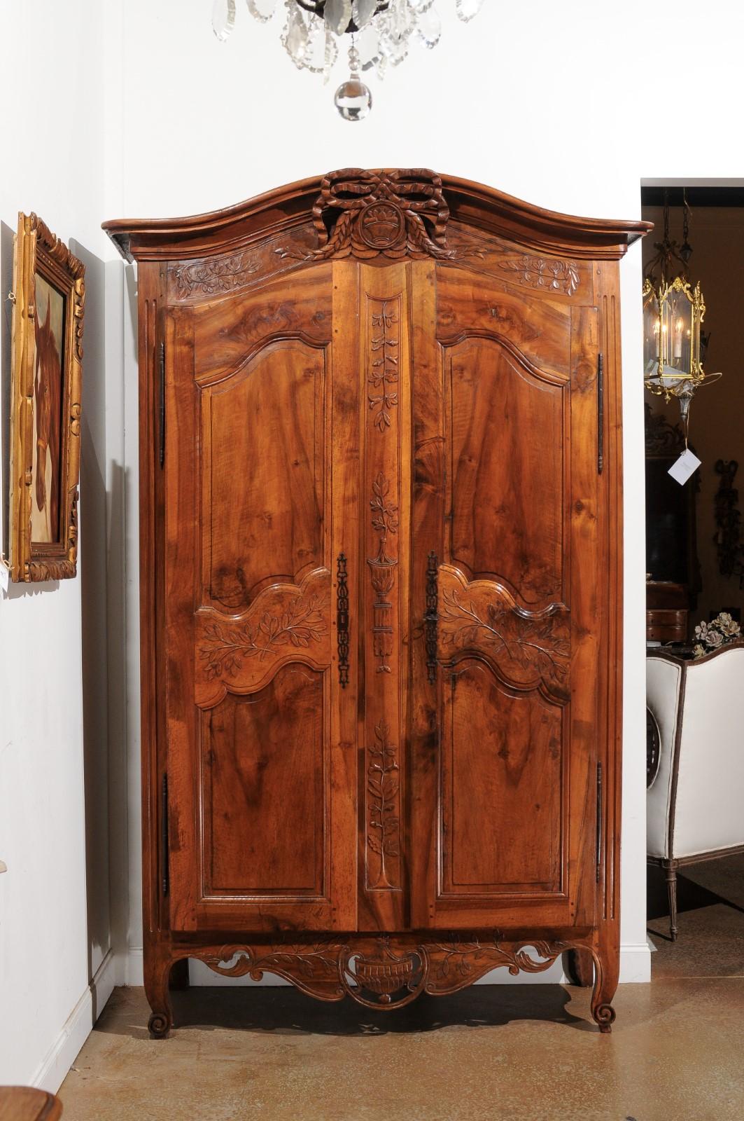 A French Transition style Provençal wedding armoire from the 19th century, with chapeau de gendarme top and carved motifs. Created in Provence during the 19th century, this Southern French wedding cabinet showcases the delicate transition of style