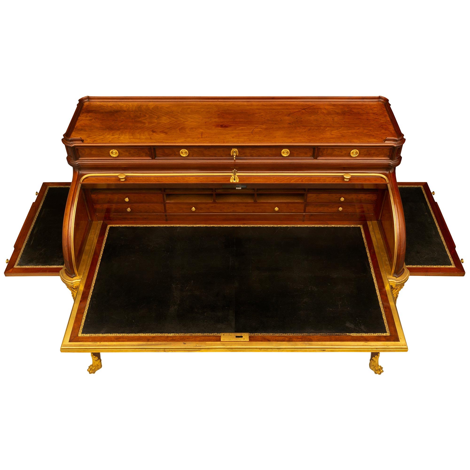 An impressive and palatially scaled French 19th century Transitional st. Moucheté Mahogany and ormolu Bureau à Cylindre desk. The exceptional thirteen drawer roll top desk is raised by elegant cabriole legs with fitted ormolu sabots with handsome