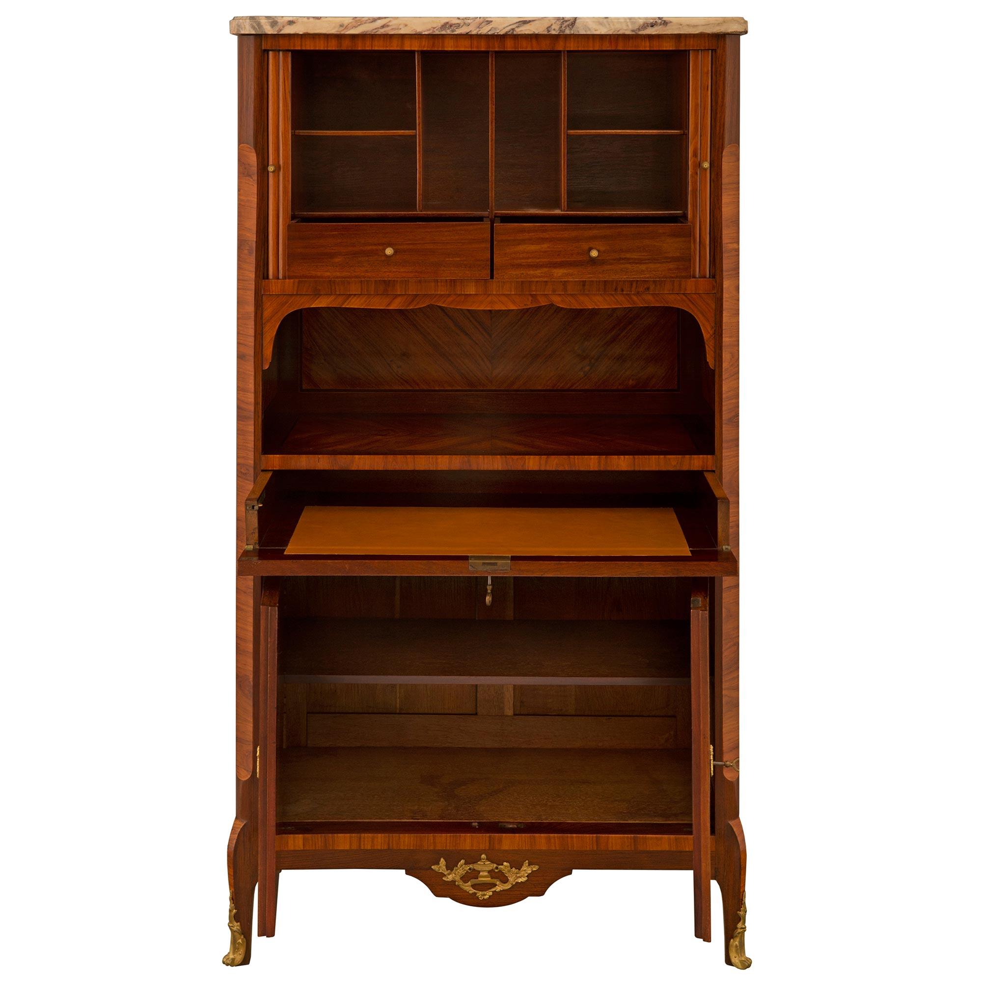 A fine 19th century French transitional cabinet/ secretaire. The whole is raised on cabriole legs with ormolu sabots below two quarter veneered tulipwood and kingwood doors. Above is a drawer opening up to a writing surface with a brown leather