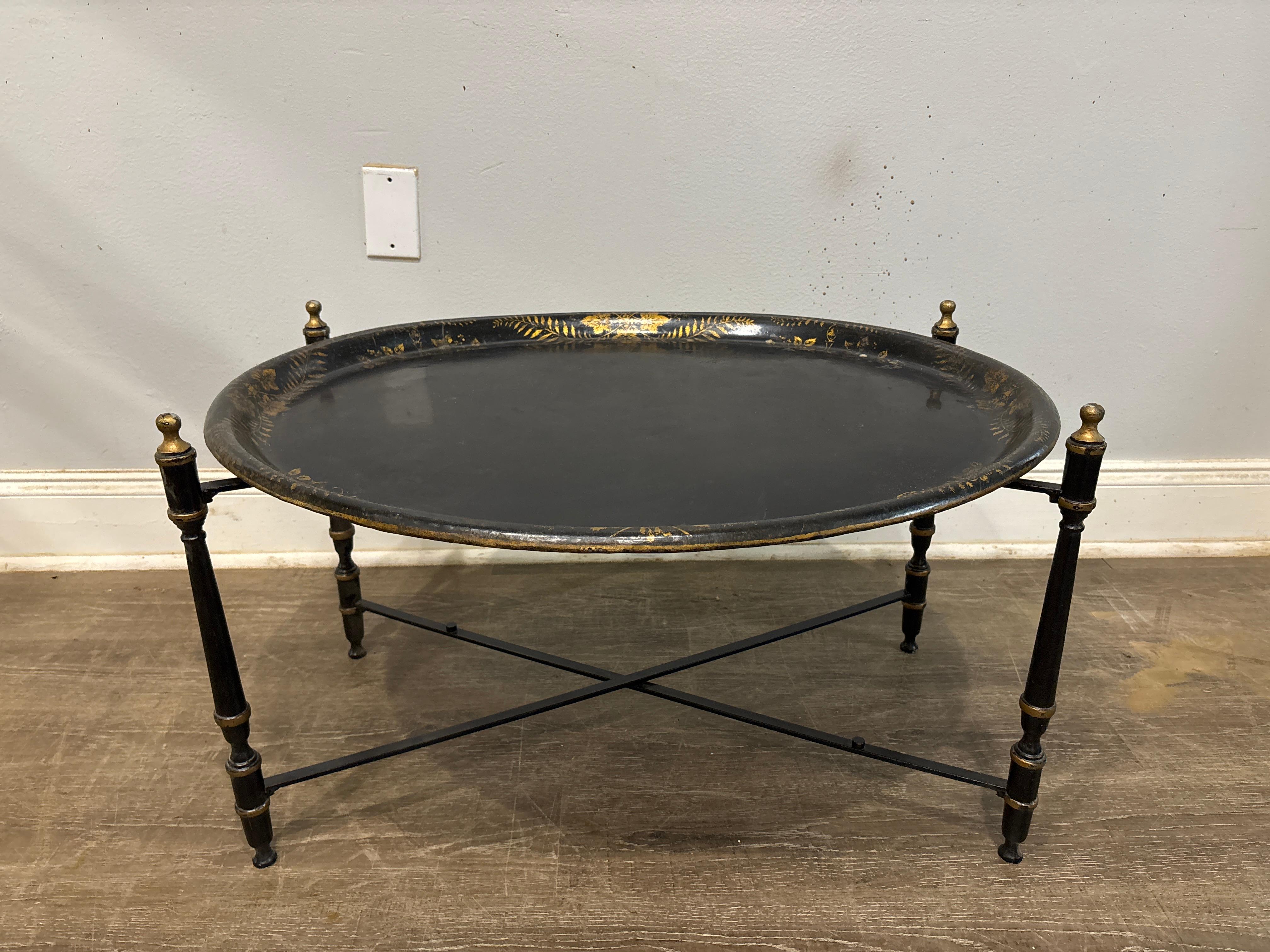 This charming piece is made of tole lacquered in black with gilt patterns.