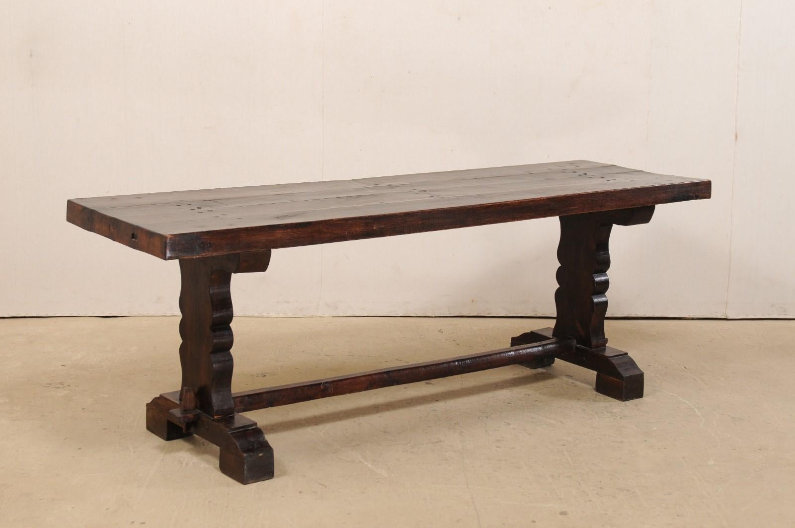 A French wooden console table from the 19th century. This elegant antique table from France has a rectangular-shaped top, just over 7 feet in length, which is supported by a pair of trestle legs (with curvy carvings down their sides), and braced
