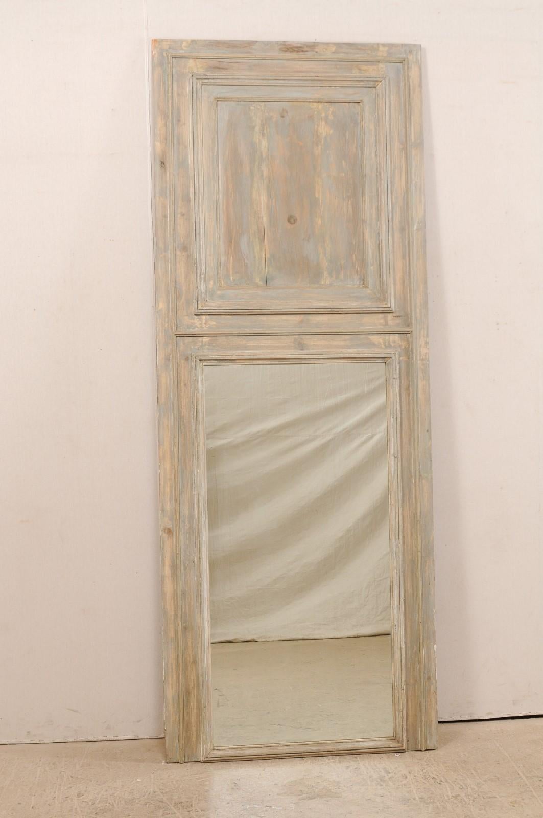 A tall French painted wood trumeau mirror from the 19th century. This antique mirror from France features clean, straight-line molding and trim, with typical trumeau design of wooden plaque-style top over mirror below. It is a nicely sized mirror,