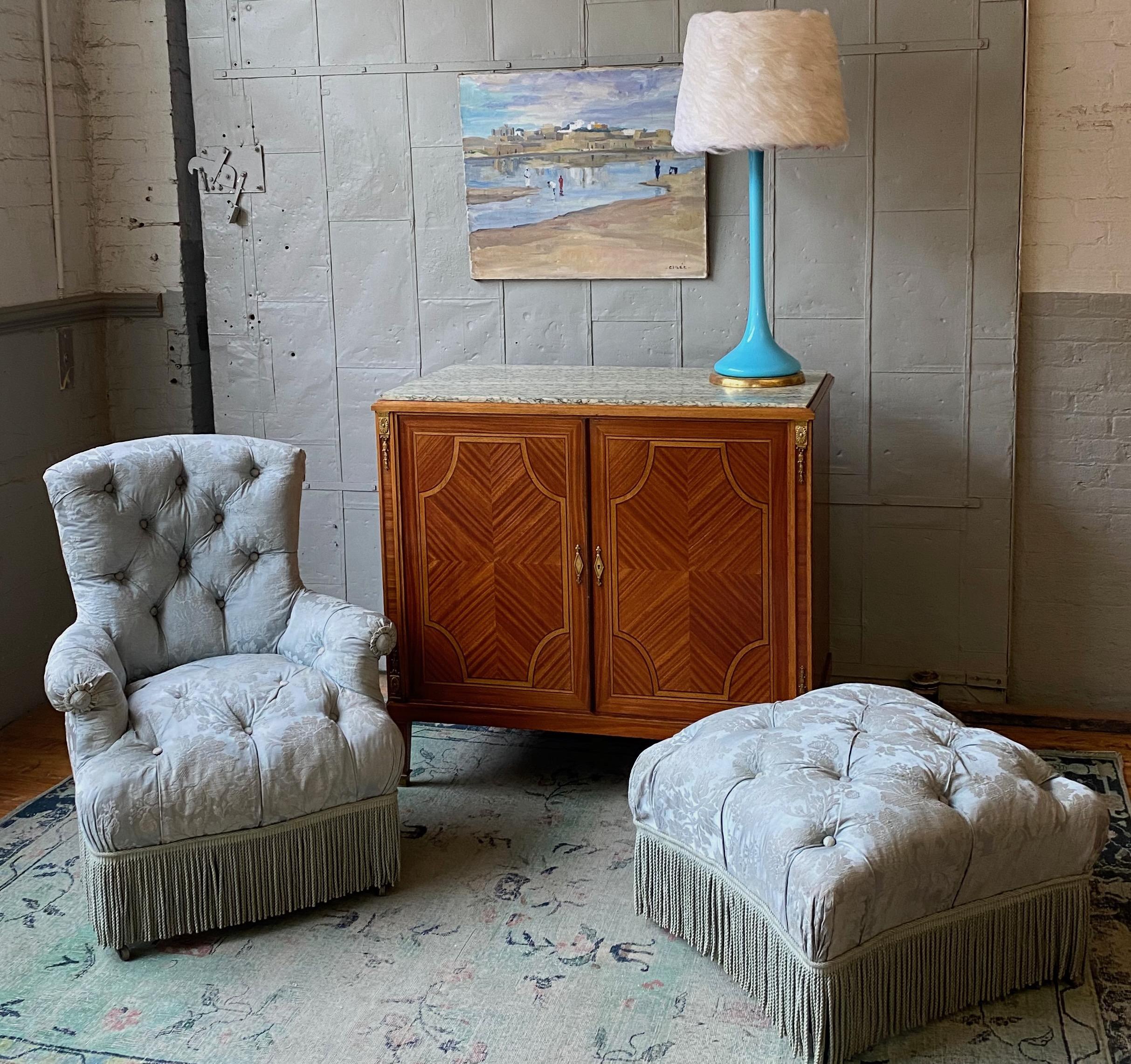 Fauteuil touffeté français du XIXe siècle aux proportions merveilleuses et ottoman assorti, tapissé de damas de soie bleu clair avec frange bullion assortie. Cet élégant fauteuil et ottoman est le complément parfait de votre traditionnel  en