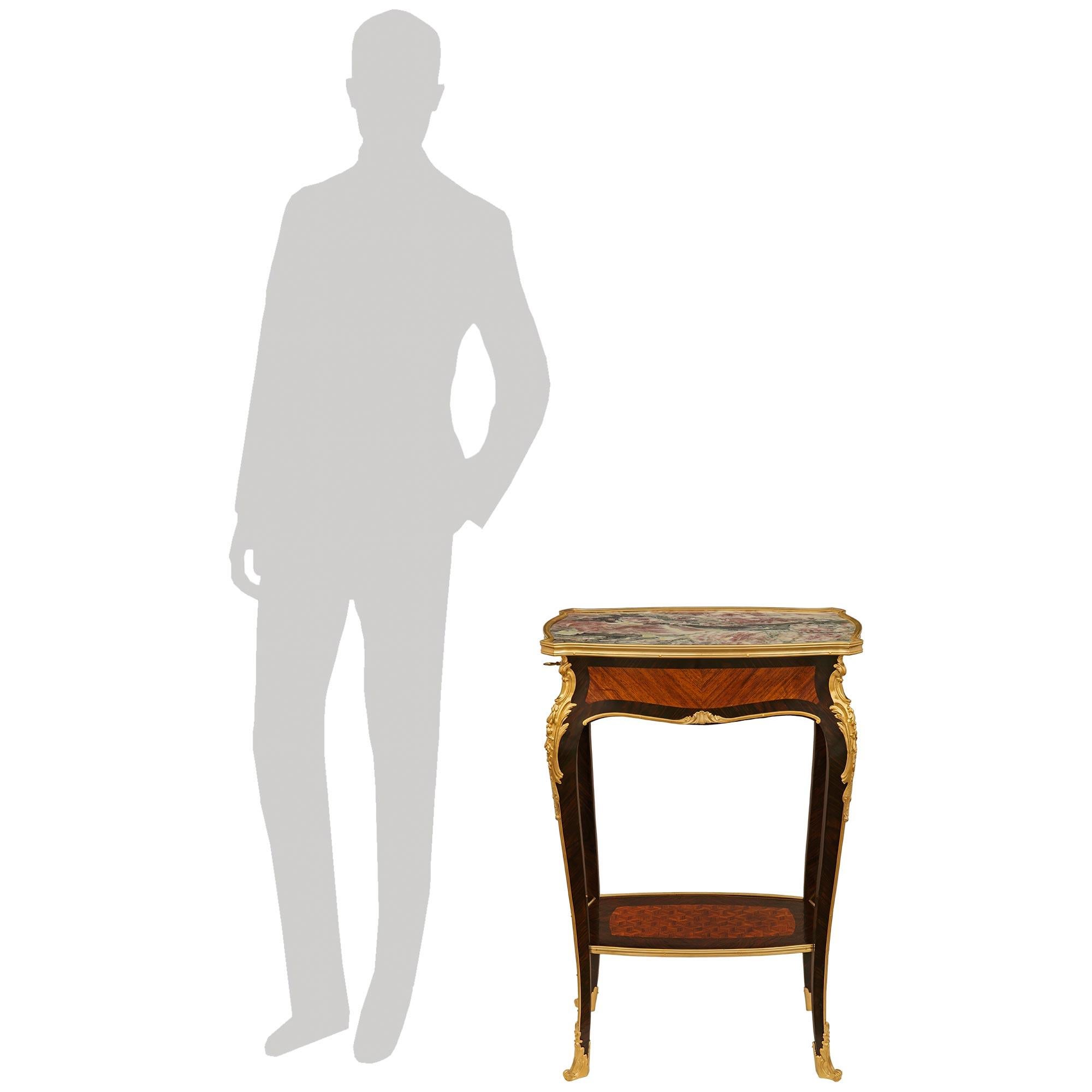 Elegante mesa auxiliar francesa del siglo XIX de estilo Luis XV de madera de tulipán, kingwood, ormolu y mármol. Esta impresionante mesa se alza sobre cuatro alargadas y esbeltas patas cabriolé decoradas con monturas superiores de Ormolu con hojas