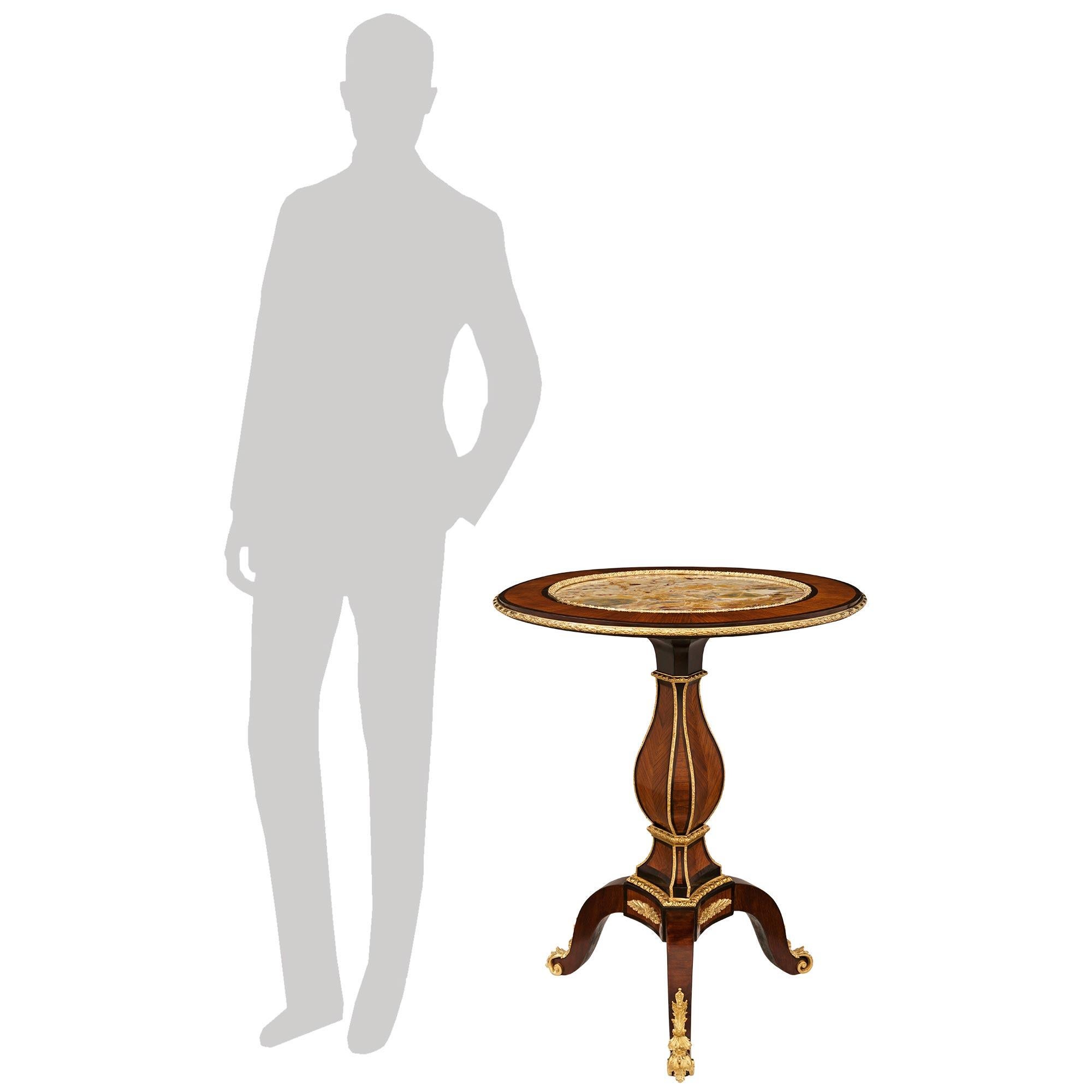 Un elegante e decoratissimo tavolino con piano inclinato in legno di tulipano, Kingwood, Ormolu e marmo Fleur de Pêcher del XIX secolo. Questo meraviglioso tavolo è sollevato su una base a treppiede a volute, sostenuta da sabot in Ormolu con