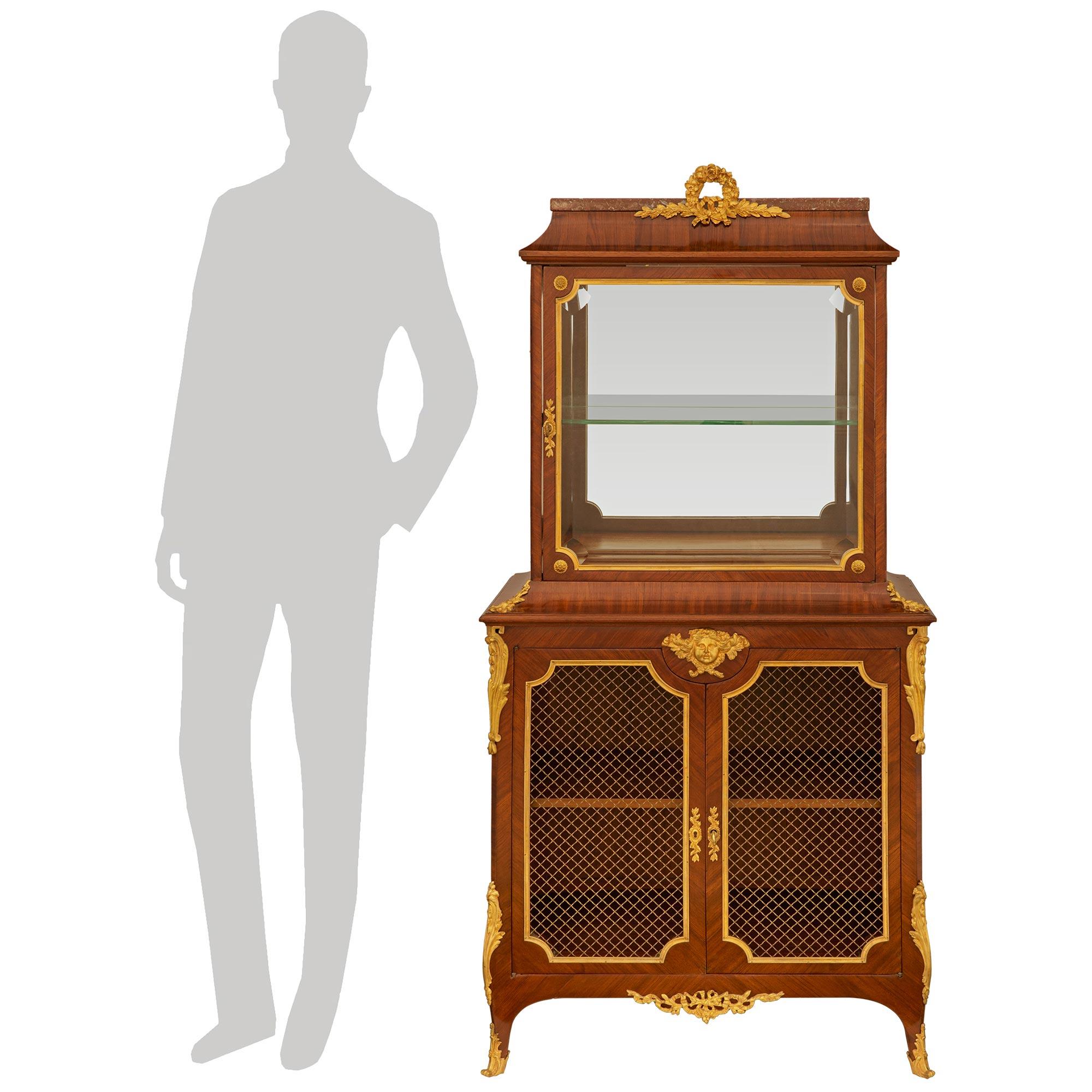 Elegante vitrina de estilo Transicional francés del siglo XIX de gran calidad. Tulipwood, Ormolu y Mármol. Este hermoso mueble se eleva sobre patas cabriolé de madera de tulipán con sabots de Ormolu y monturas foliadas en las esquinas que conducen a