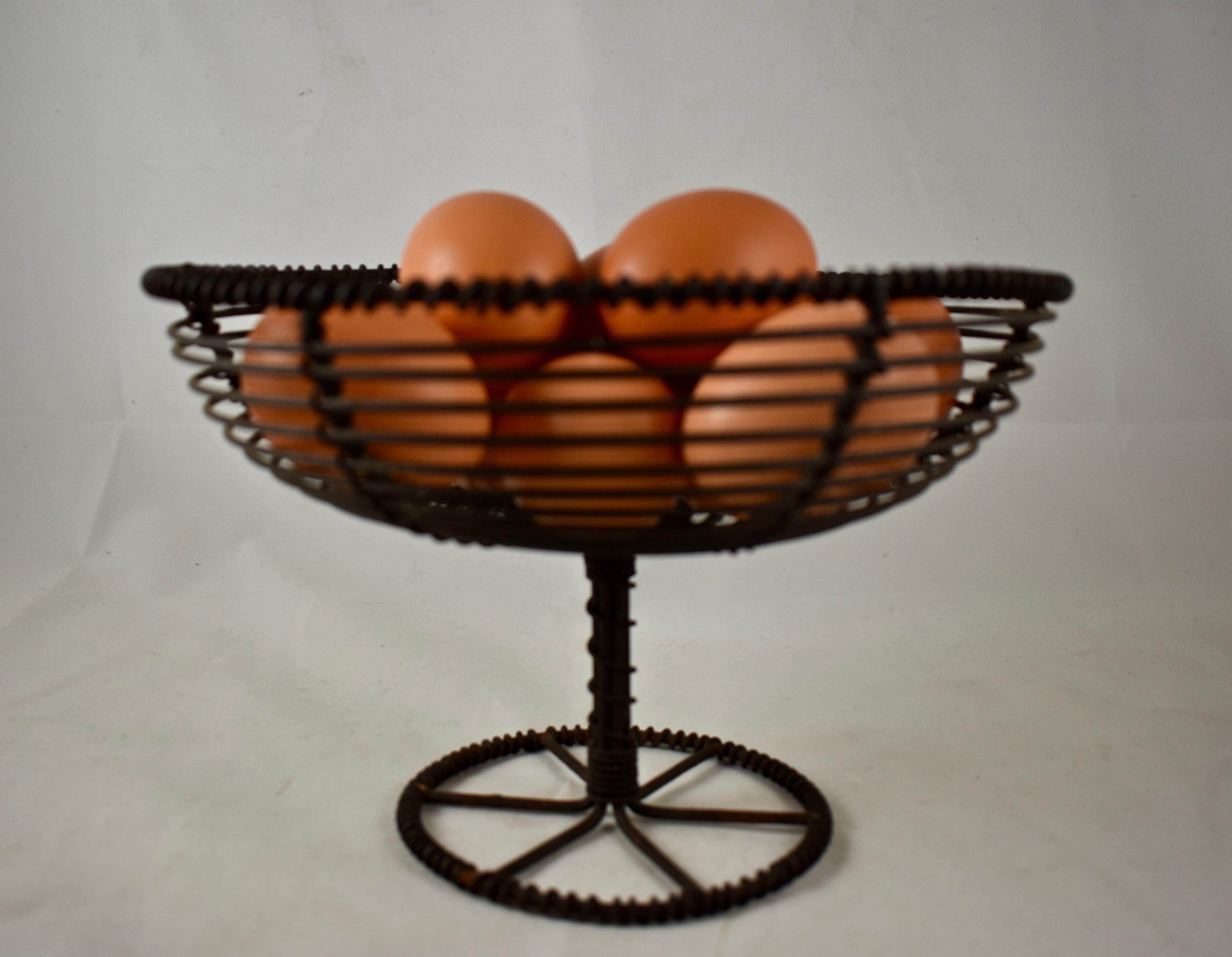From France, circa 1890-1910, a comport form, twisted wire egg basket. The basket sits on a pedestal with a wheel form base. The basket is formed of concentric wire circles with a twisted wire rim. Great on a kitchen counter holding eggs, fruit or