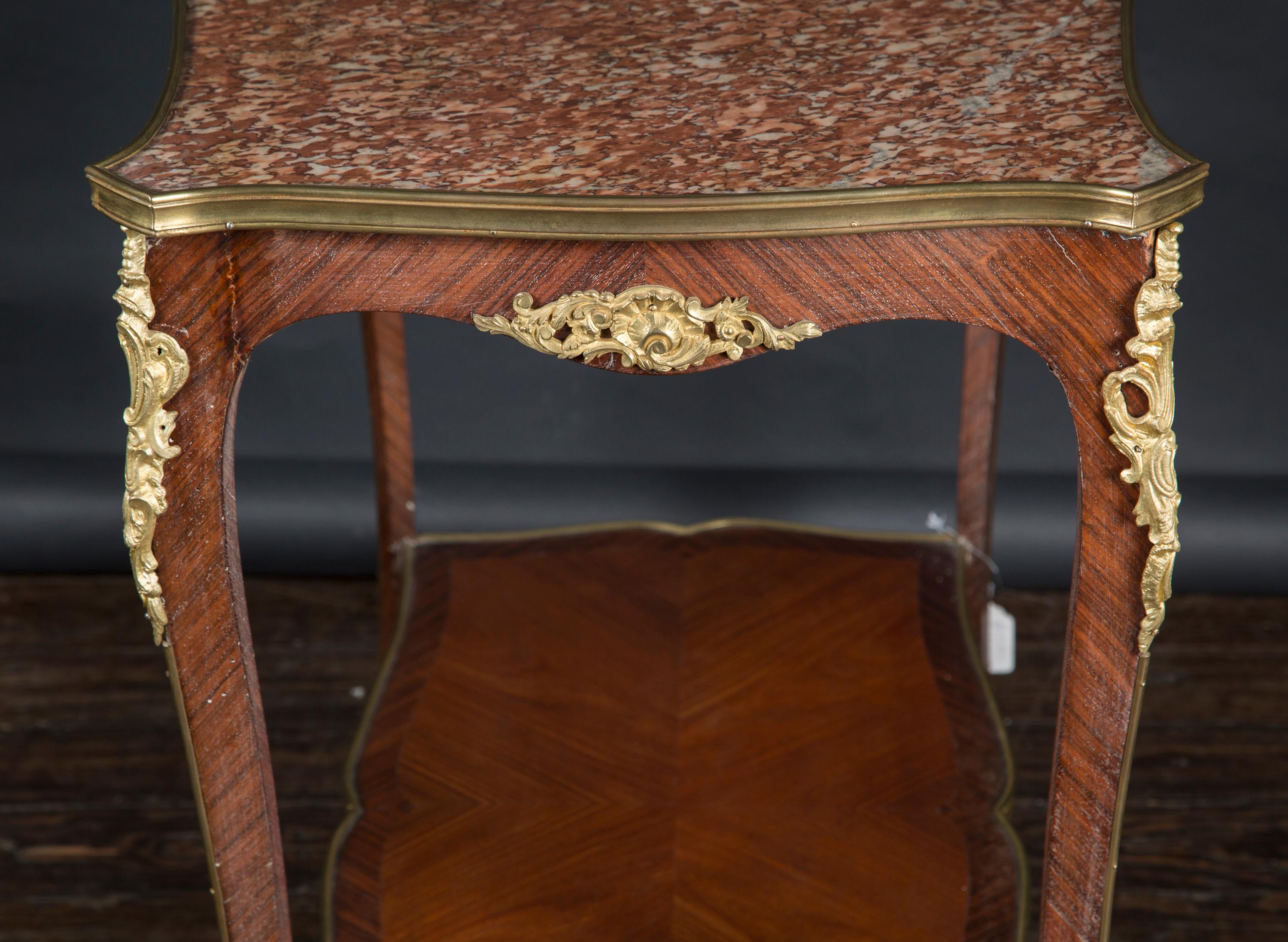 Cette belle table à deux niveaux en bois satiné et marbre présente des montures en bronze conçues à la manière de Louis XV, et repose sur quatre pieds en bois en forme de cabriole. Datant du 19e siècle, cette pièce antique française présente un