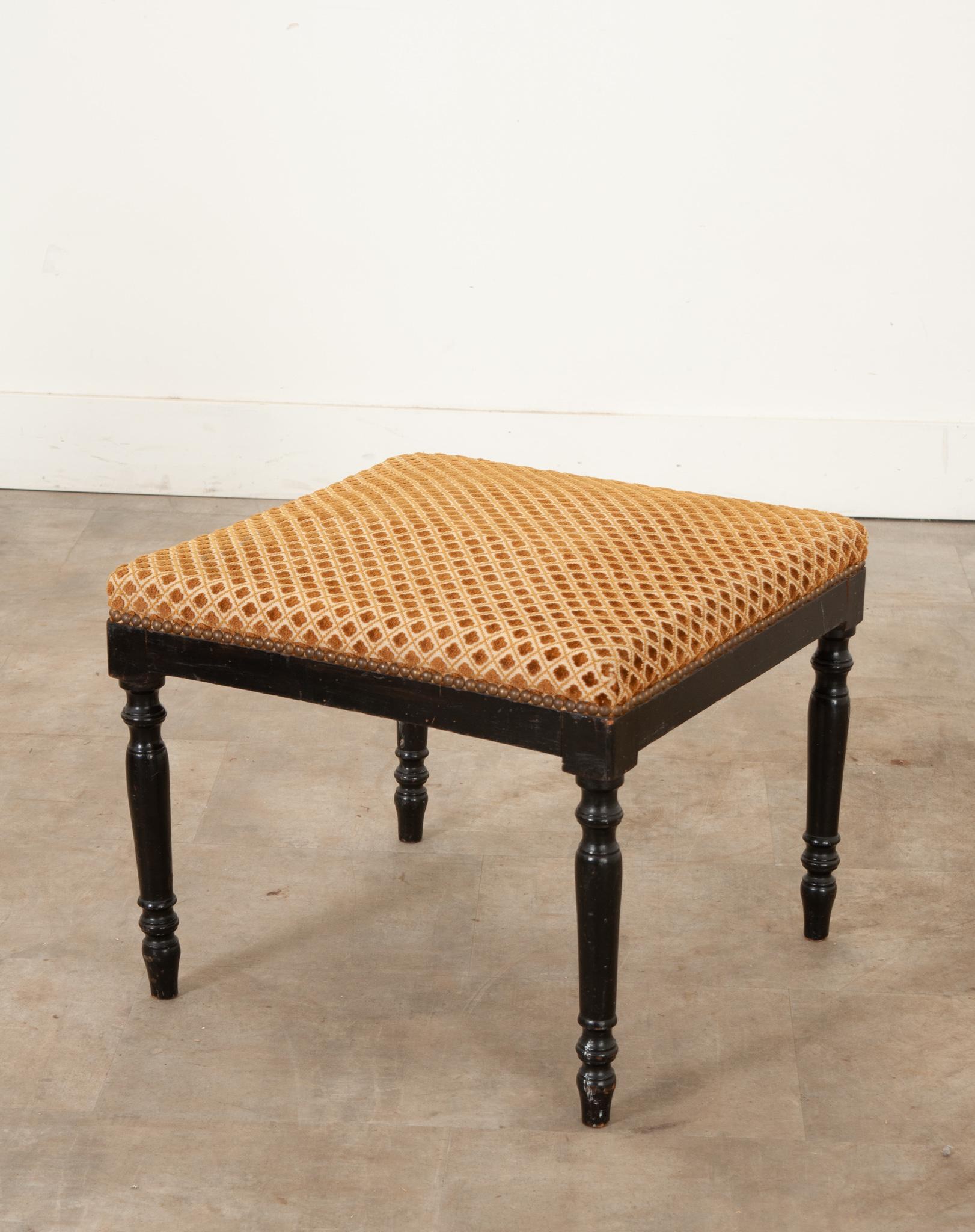 A lightweight square stool from the late 1800’s. The comfortable cushion is covered in cut velvet upholstery and has a diagonal quatrefoil design with nailhead trim. Raised on turned wood legs with an ebonized finish. Be sure to view the detailed