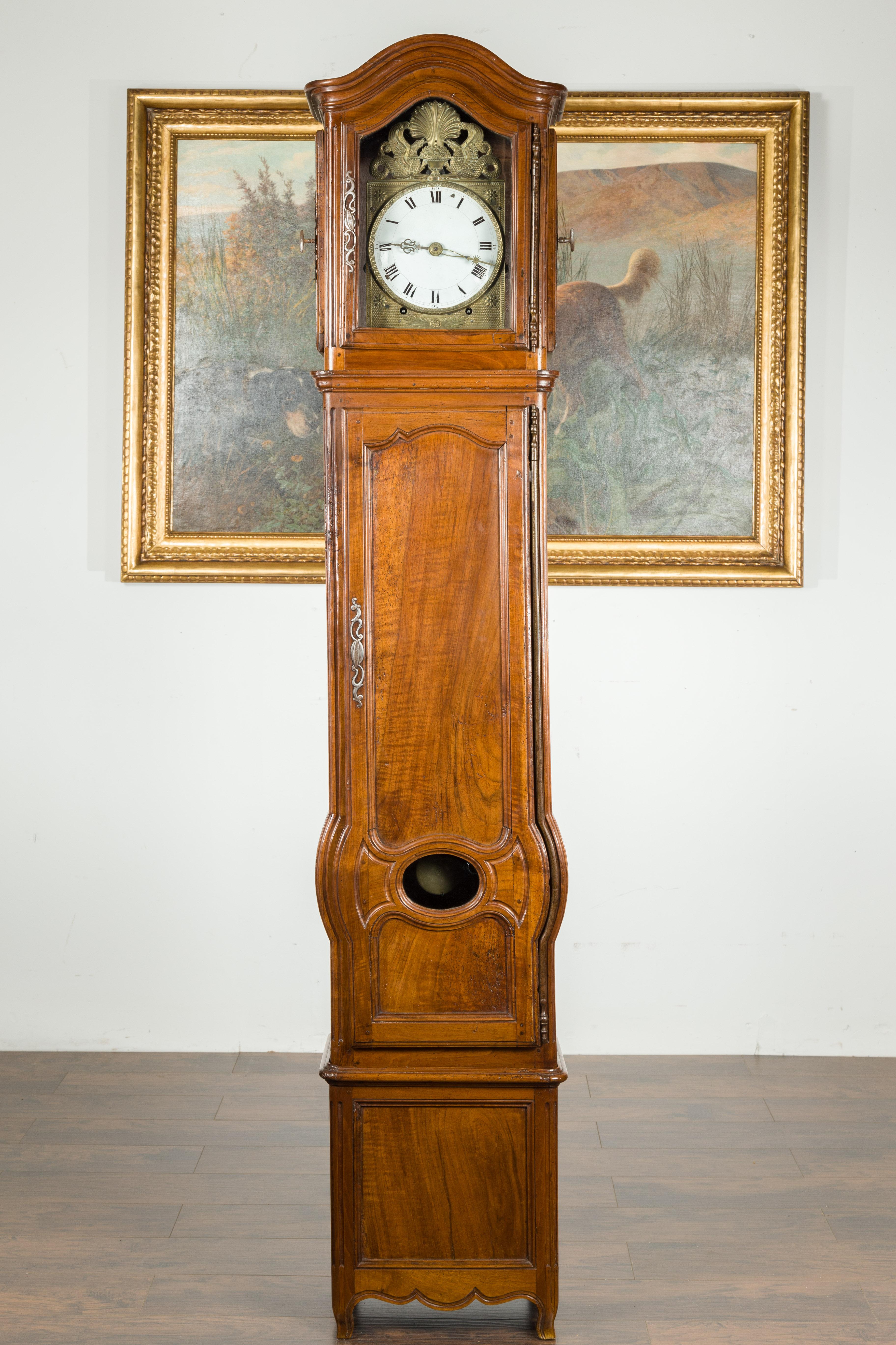 A country French walnut grandfather clock from the 19th century, with brass Empire style griffin figures and 'chapeau de gendarme' top. Created in France during the 19th century, this grandfather clock attracts our attention with its bonnet top and