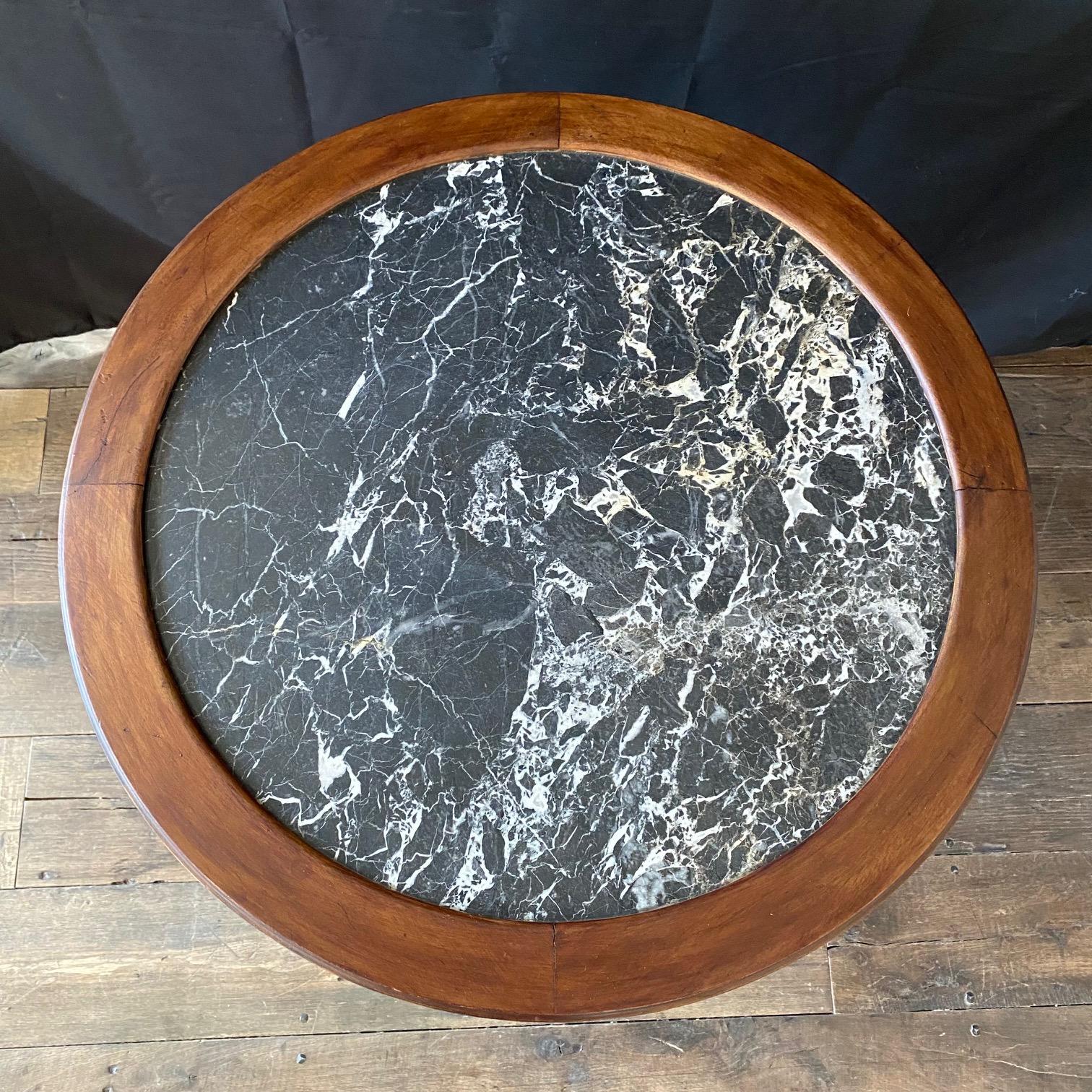 Cette exquise table bouillotte ou table d'appoint en noyer français est un complément parfait à tout espace de vie élégant, et présente un luxueux plateau en marbre qui ajoute une touche de sophistication et de classe à la pièce. Le design complexe