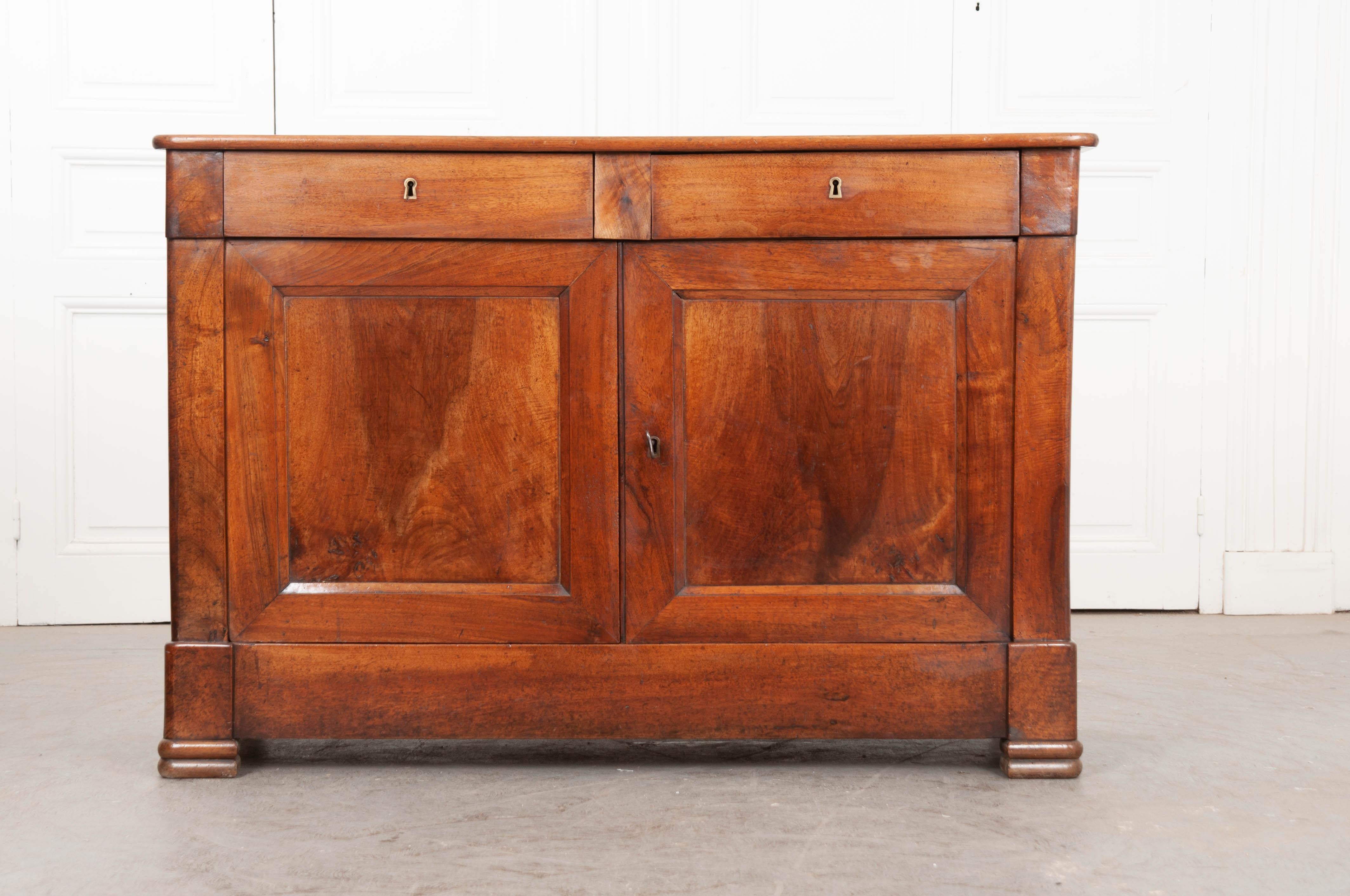 A handsome walnut buffet, made in France, circa 1880. The case piece has been constructed in a transitional style that is heavily influenced by the Louis Philippe period. The apron contains two drawers, each with working locks. Two paneled doors