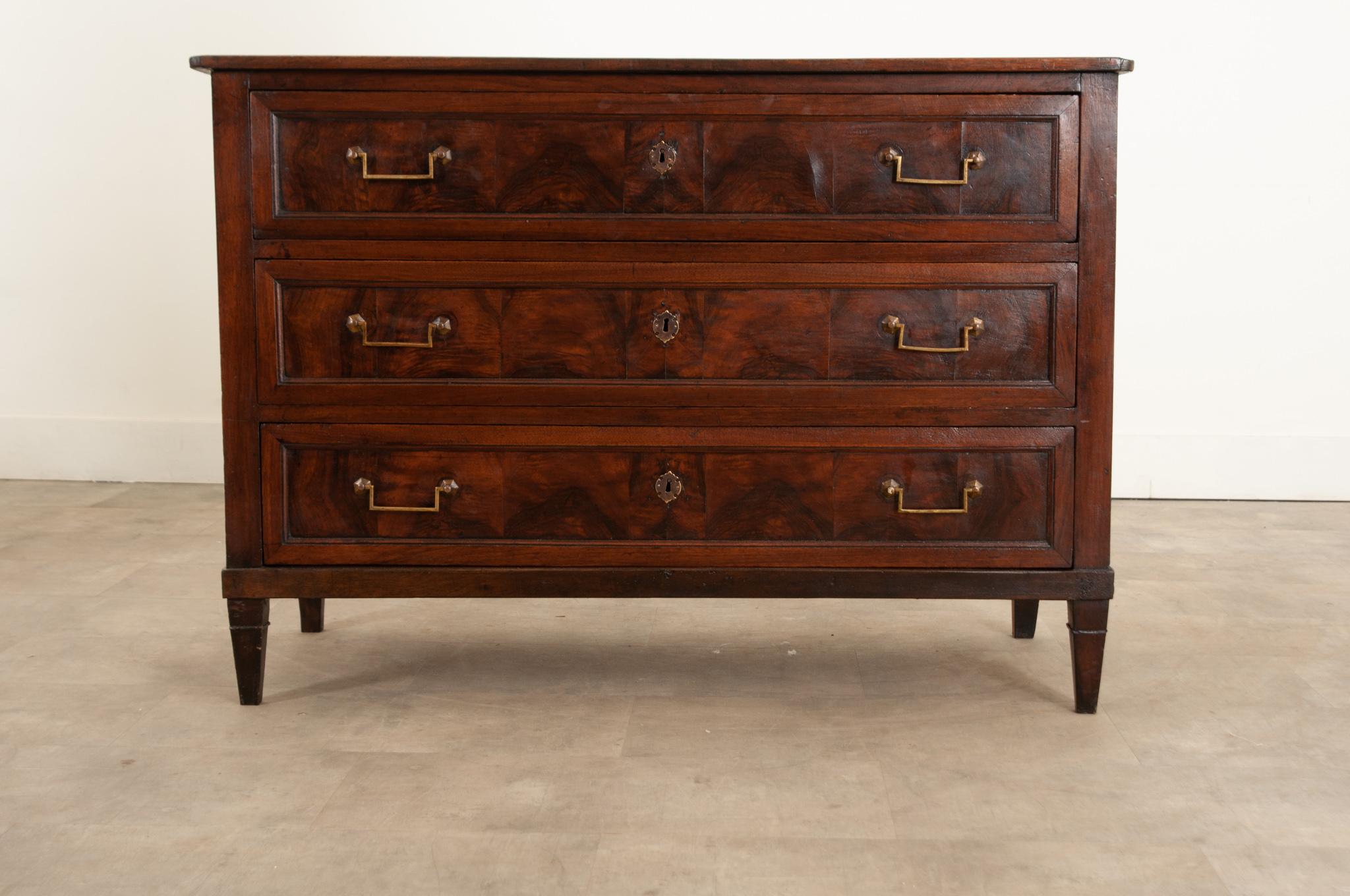 A stylish early 19th Century French commode with a smooth polished top made of a single large board. Hand-crafted in France circa 1810 this commode features three molded drawers with burl walnut panels flanked by canted corners. Each drawer is