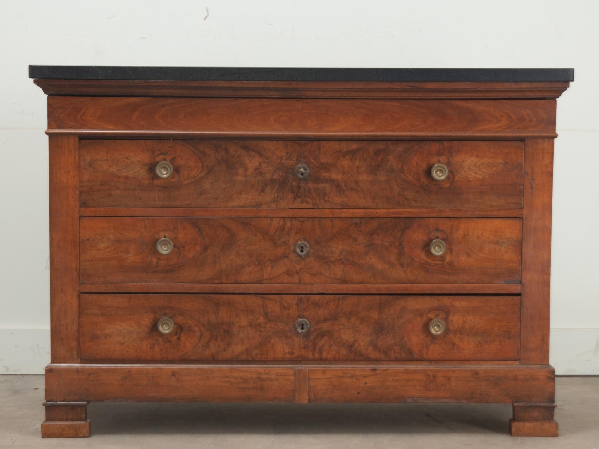 A French walnut commode from 19th Century France. The black marble top is more recent and compliments the cabinet base. There are four total drawers in this chest. The first drawer is hidden just below the new marble top. Below are three burl and