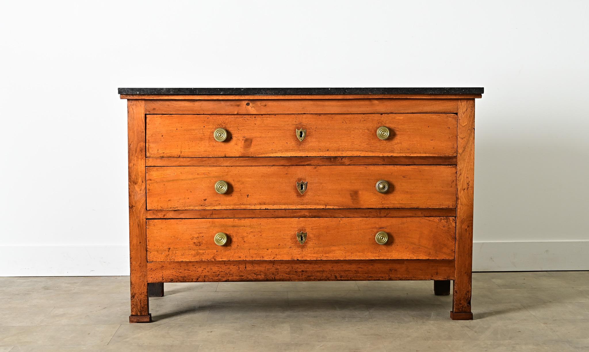 A handsome French walnut and fossil-marble commode from the 19th century, closely resembling the Empire style with strong proportions and quality the period is known for then pared down to its most necessary elements. The dark stone top reveals tiny
