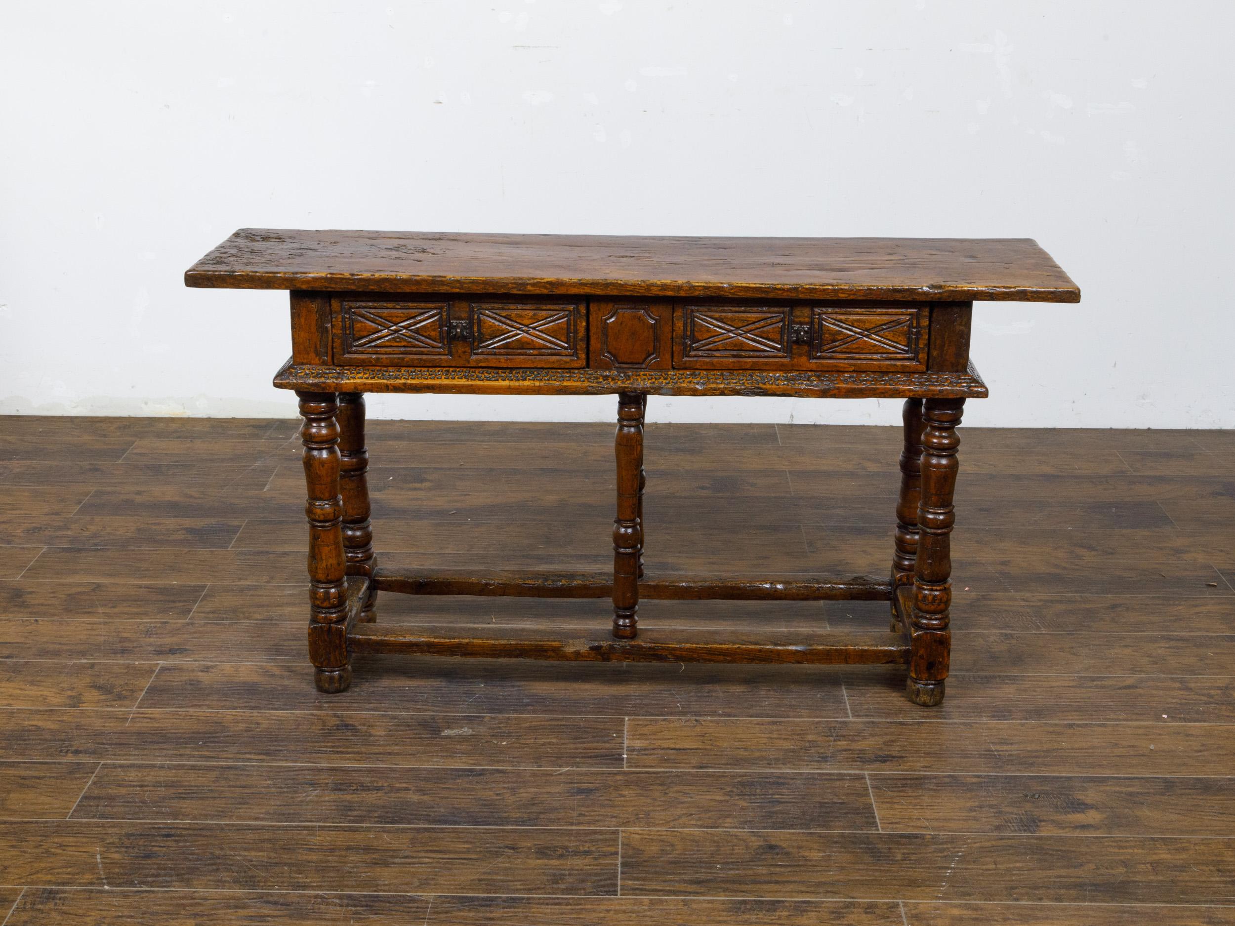 A French walnut console table from the 19th century with two carved drawers, turned legs and plain side stretchers. This charming French walnut console table from the 19th century features a rich, warm patina that highlights the natural beauty of