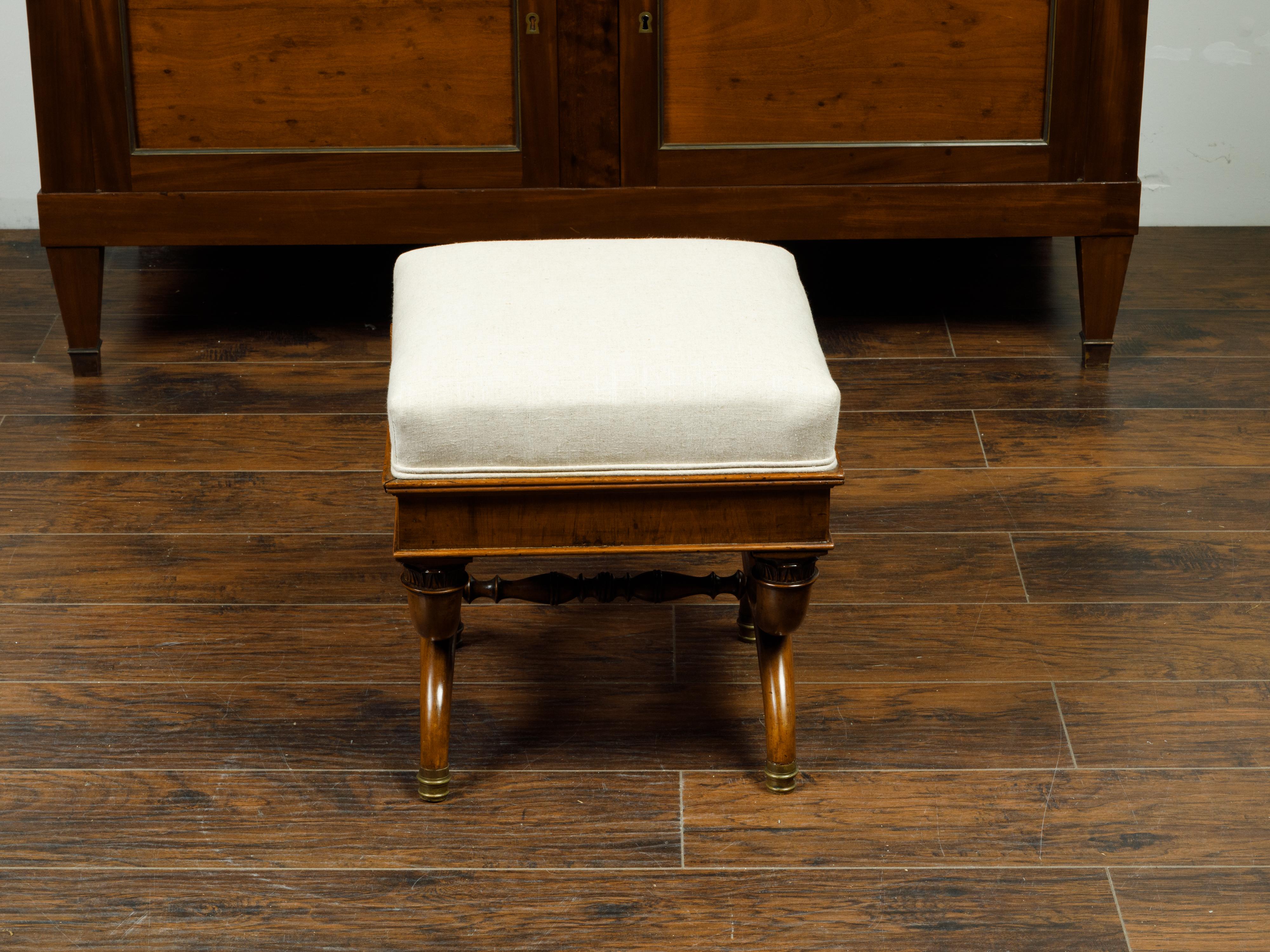 A French walnut X-form curule stool from the 19th century, with Corinthian capitals and new upholstery. Created in France during the 19th century, this walnut stool features a square seat newly reupholstered with a neutral toned double welt fabric