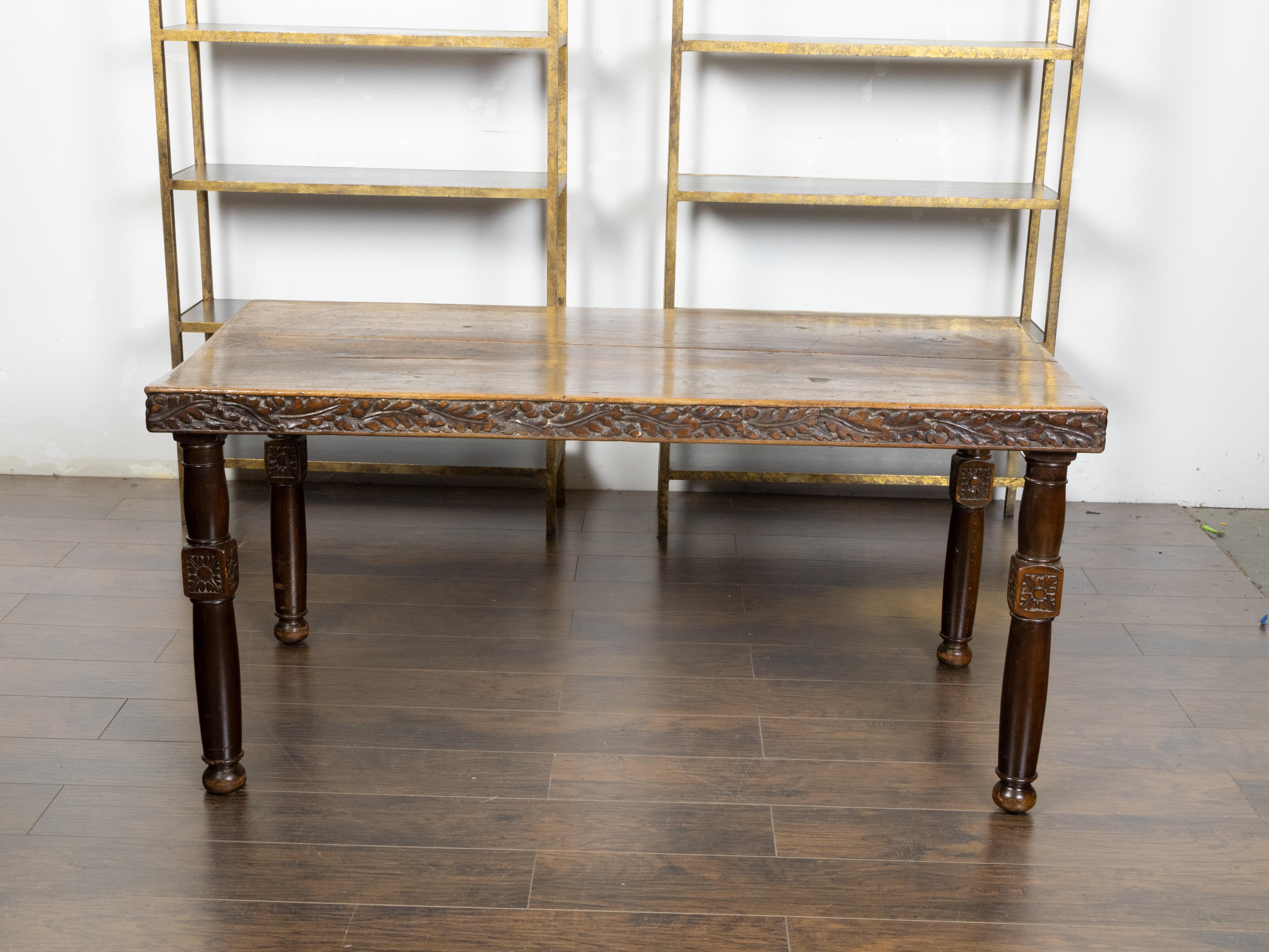 A French walnut dining room table from the 19th century, with foliage-carved apron, turned legs, rosettes and bun feet. Created in France during the 19th century, this walnut dining room table features a rectangular planked top with nicely