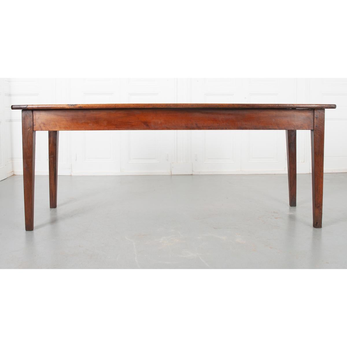 This is a French 19th century walnut dining table. It has one wide plank in the center of the top with smaller planks on either side. The patina is wonderful. It has a nice wide apron with tapered French legs. It is circa 1840.
 