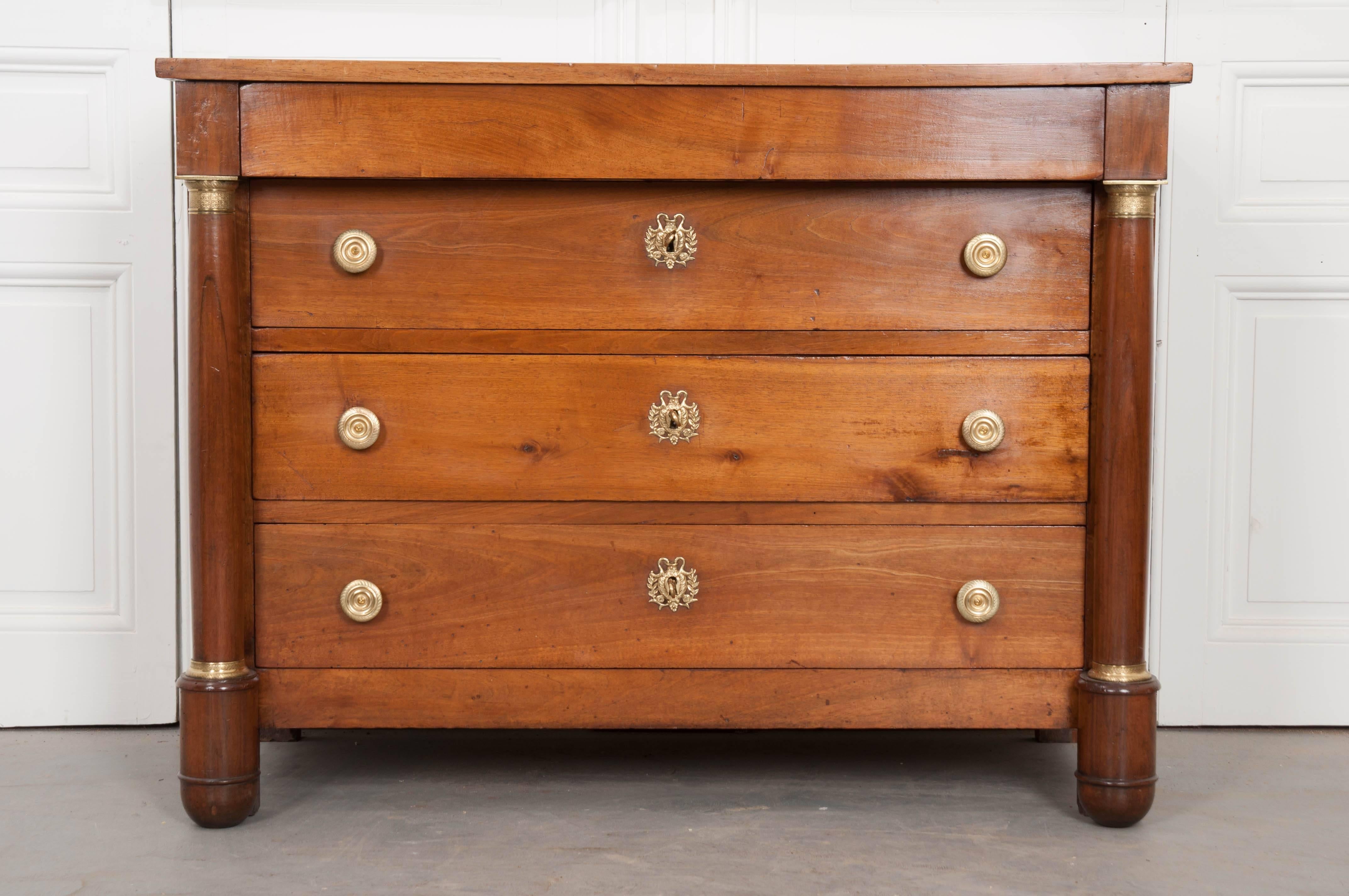 Great care was taken through the years to maintain this exceptional solid walnut Empire period commode from France. The commode is complete with four total drawers, the topmost being hidden in the apron. The three lower drawers are all of equal