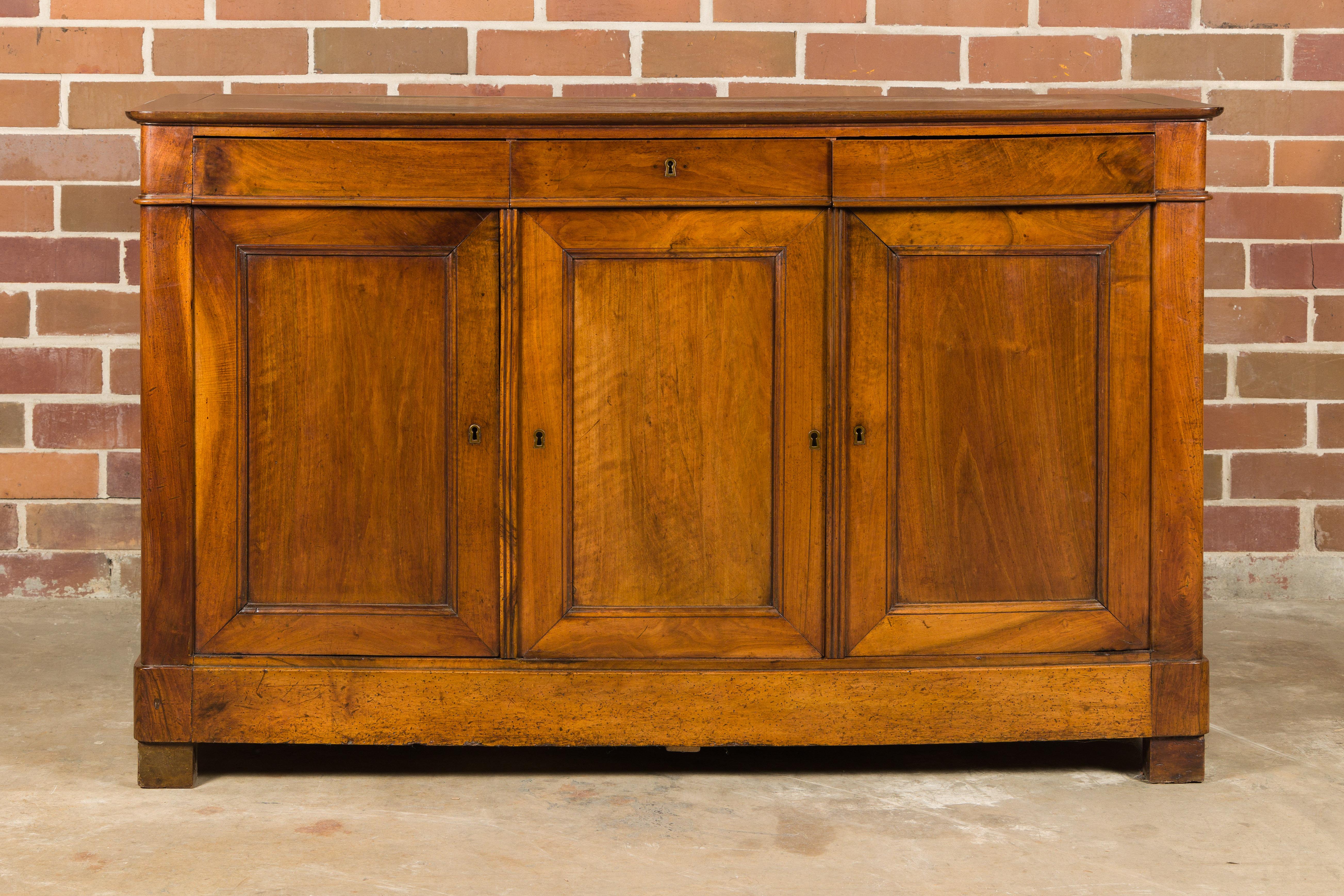 A French walnut enfilade from the 19th century with three drawers over three doors. This 19th-century French walnut enfilade exudes timeless elegance and practicality, embodying the essence of classic French design. With three drawers gracefully