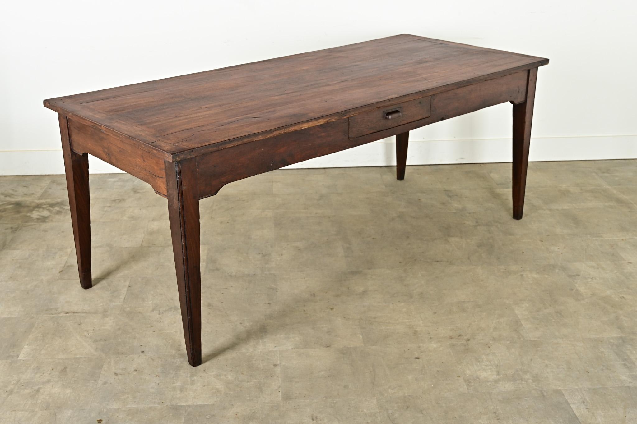 Charmante table de ferme française fabriquée au 19e siècle en noyer massif, avec des extrémités en planches à pain. La surface est légèrement ondulée en raison de l'usinage des planches, ce qui met en valeur la beauté du grain. Quelques patines dues