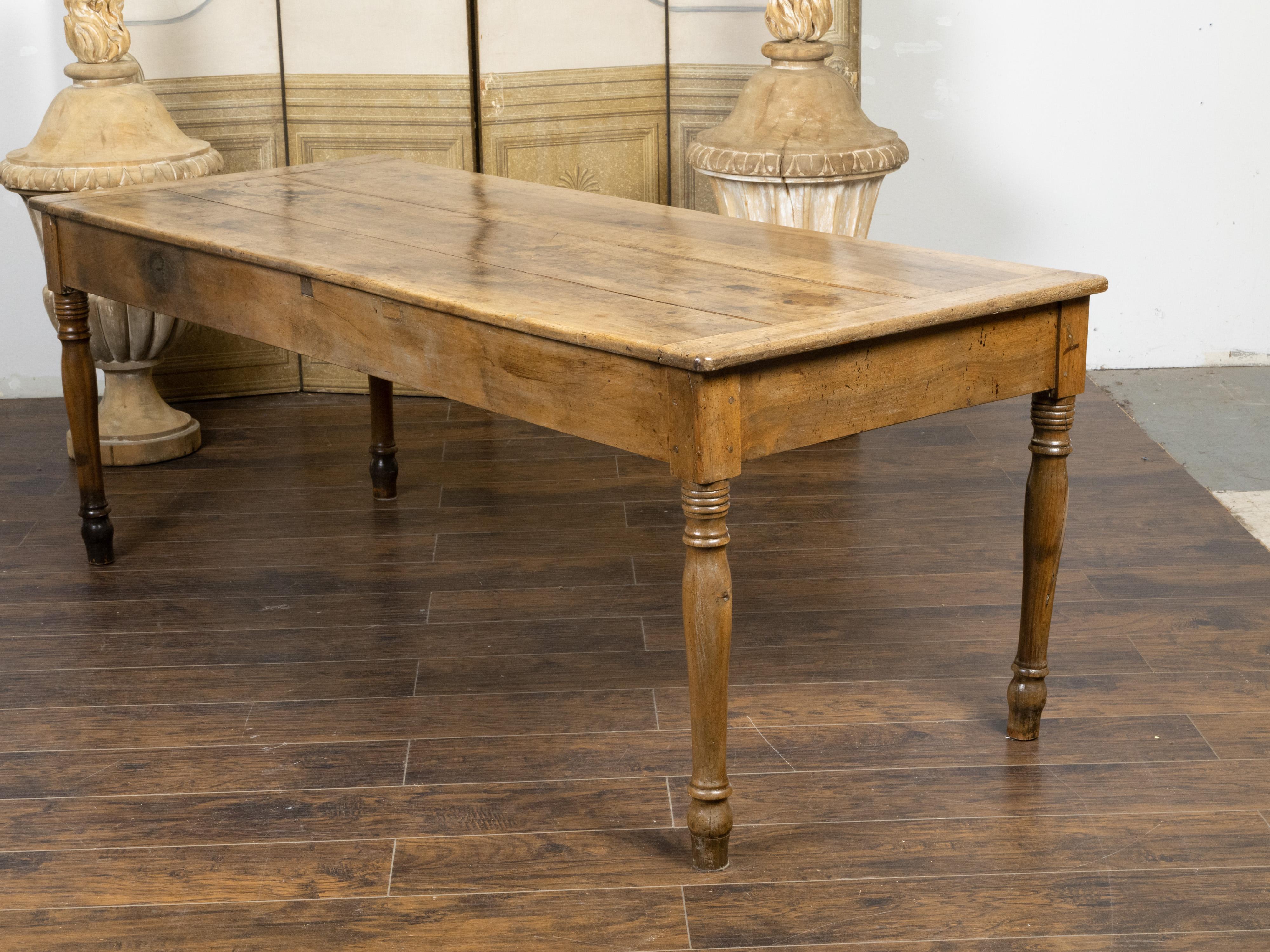 A French walnut farm dining table from the 19th century, with distressed top, turned legs and great rustic character. Created in France during the 19th century, this farm table charms us with its good proportions and nicely weathered appearance. The