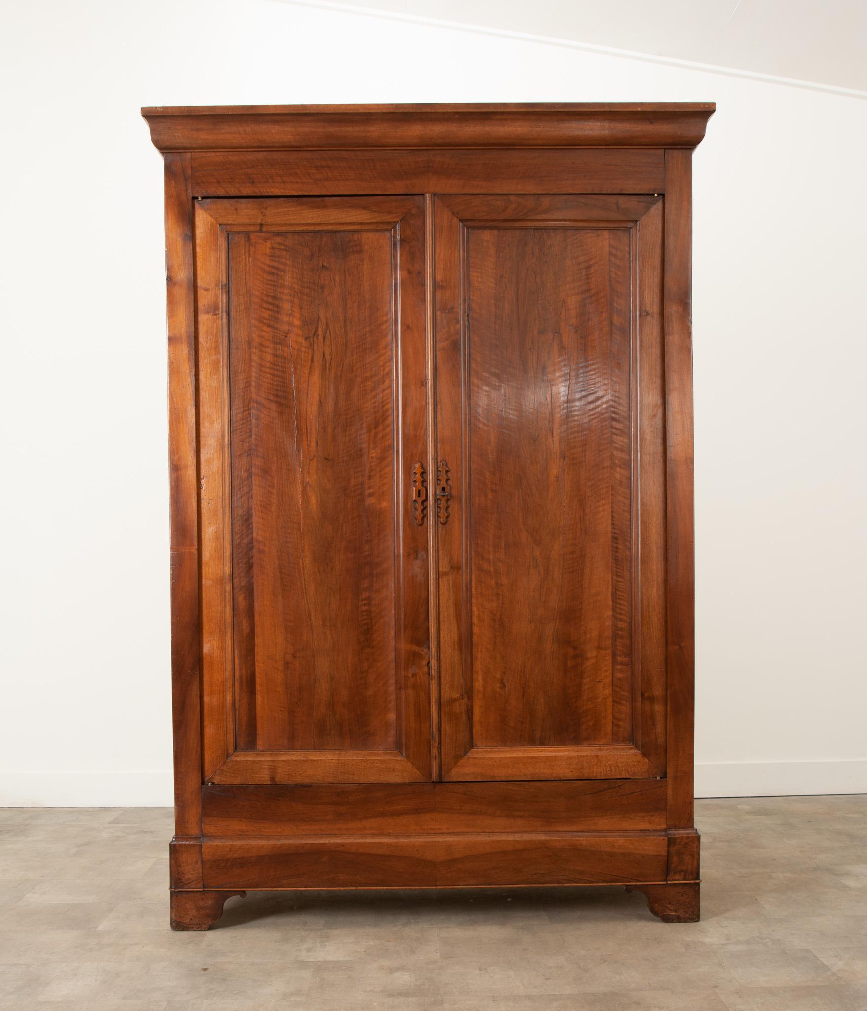 A handsome 19th century walnut armoire, made in France in the Louis Philippe style. This tall case piece has a simple, linear composition – an attribute that makes Louis Philippe pieces ideal for their versatility and placement possibilities. This