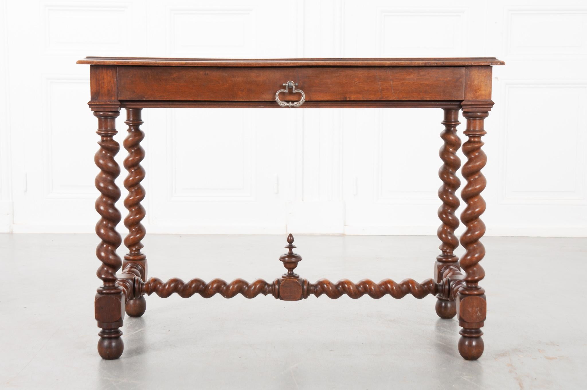 A French 19th century Louis XIII-style center table, with a beautiful walnut top. The table’s apron is simple and has one wide drawer with a styled metal pull. Four barley twist legs support the top. It has barley twist stretchers on the sides and