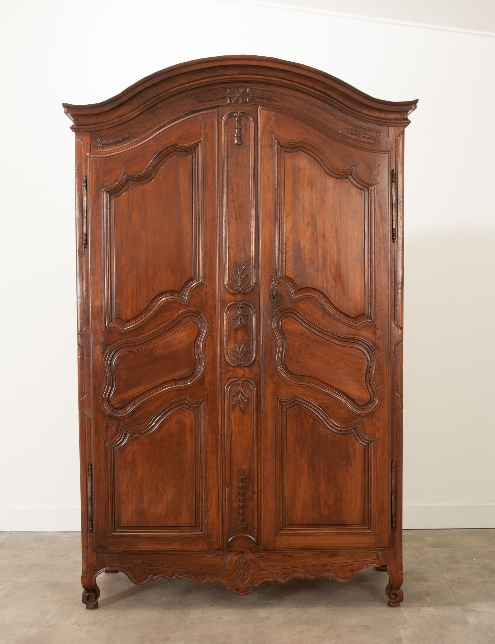 A wonderfully provincial Louis XV style armoire, handcrafted from solid walnut during the 19th century. A Chapeau de Gendarme cornice tops two doors with shapely carved panels creating a gorgeous façade with style-matching, recessed panels. They are