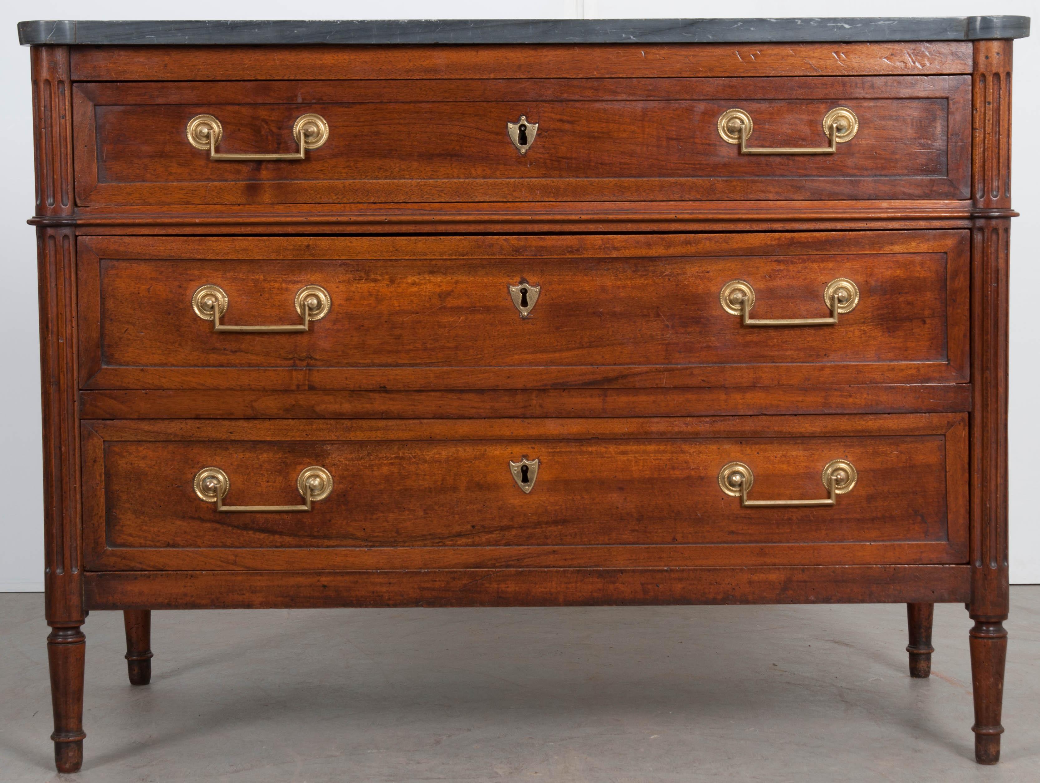 An exceptional French, solid-walnut commode, made in the Louis XVI style, circa 1850. The three-drawer case antique is topped in a wonderful gray marble top, which has been cut to fit the shaped base. It is in good antique condition with a few chips