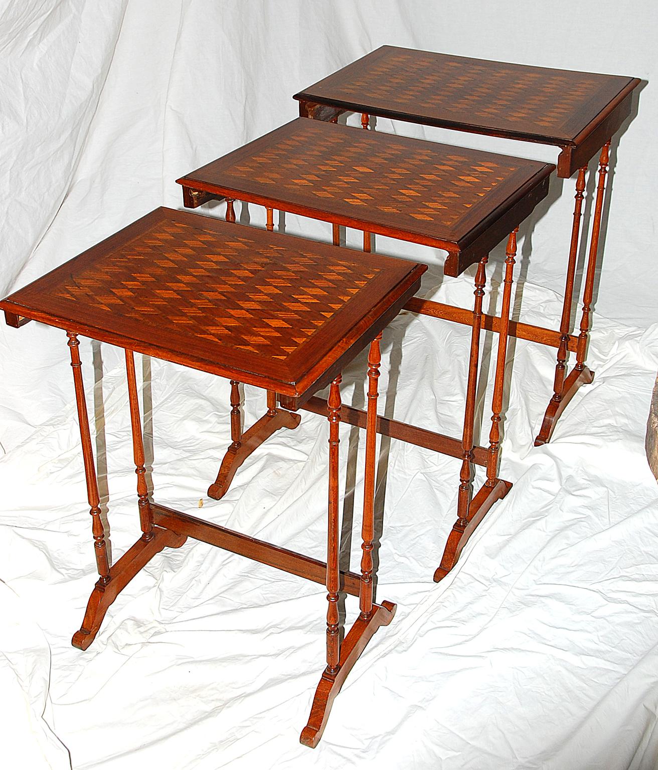 French set of three 19th century walnut marquetry nesting tables with various inlaid woods to the top and delicate turned tapered legs, curved cross stretchers, late 19th century.