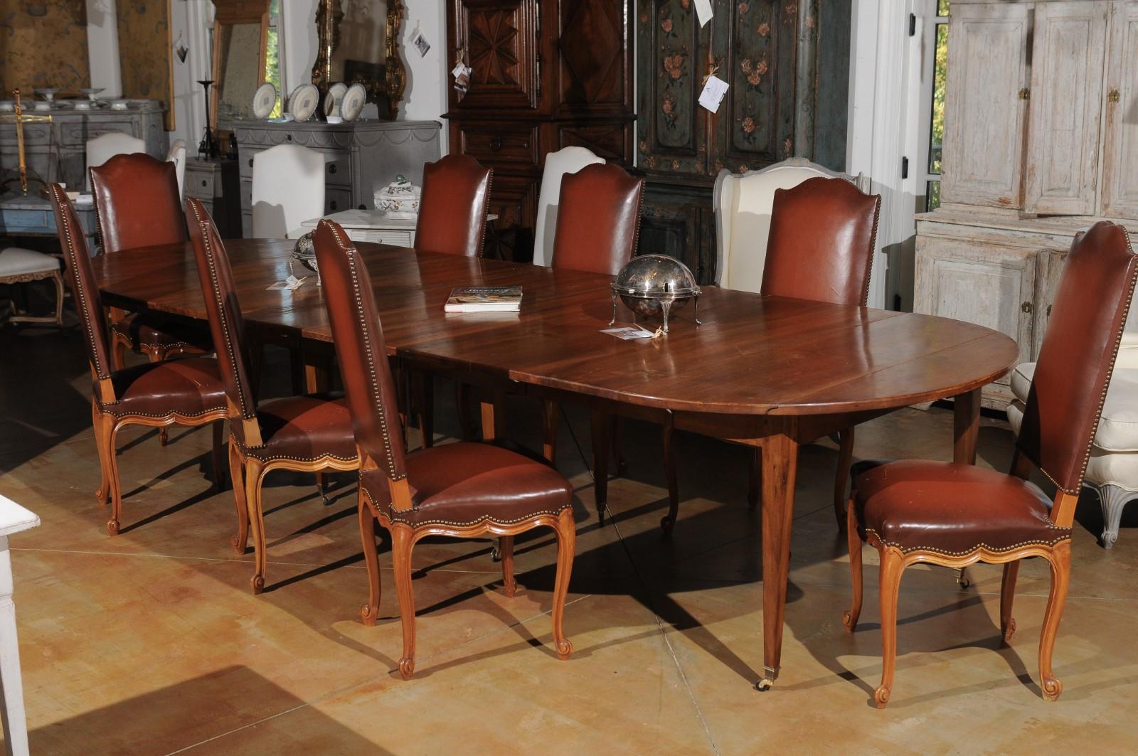 ON HOLD A French walnut oval extension dining room table from the 19th century, with five leaves, tapered legs and casters. Created in France during the 19th century, this French dining room table features a walnut oval top showcasing lateral drop
