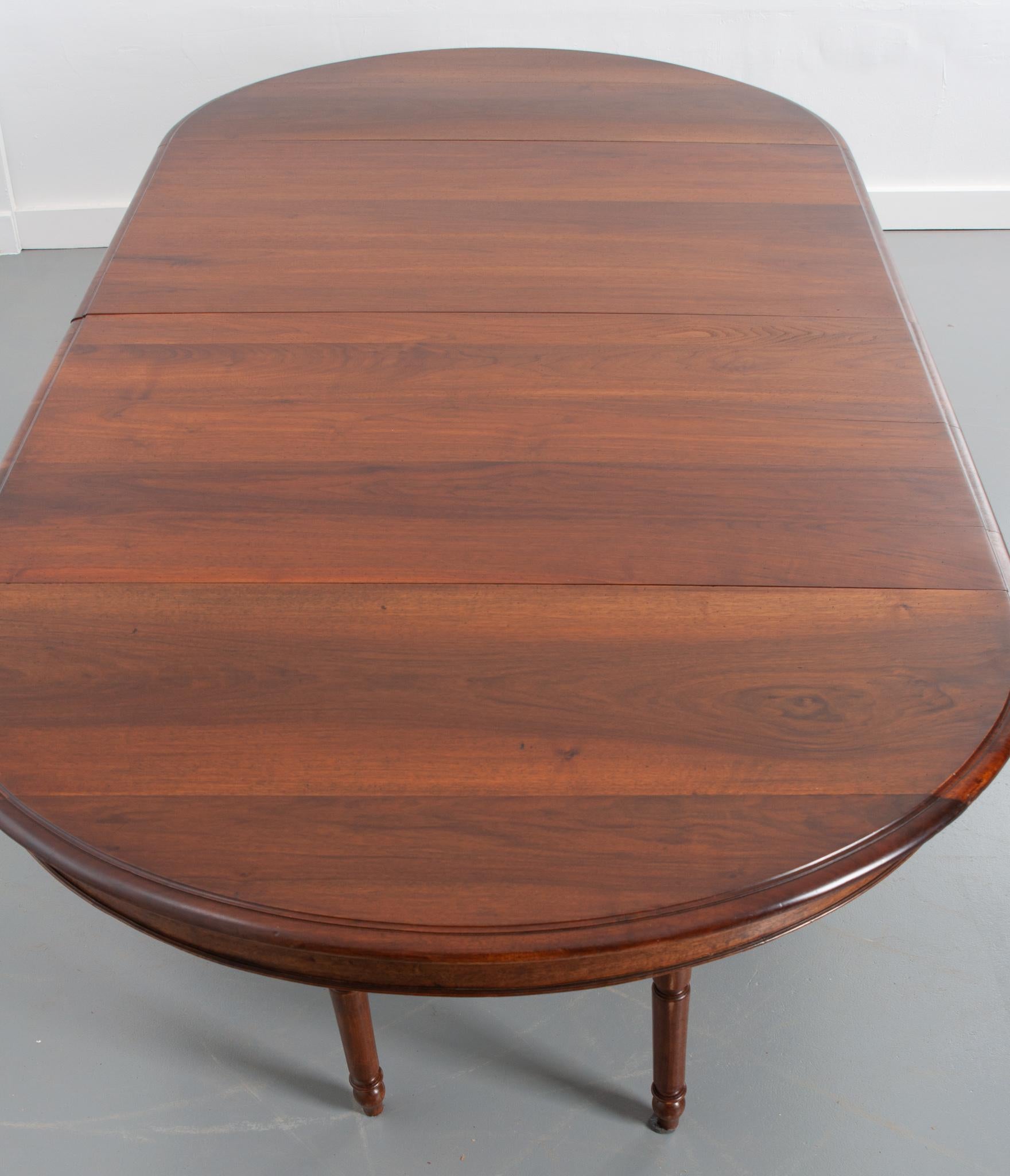 A stately French walnut oval extension table, circa late 1800s. It has two new custom leaves that convert the table from a small oval to massive table fit for a feast. The top sits over a simple apron raised on a massive reeded column pedestal with