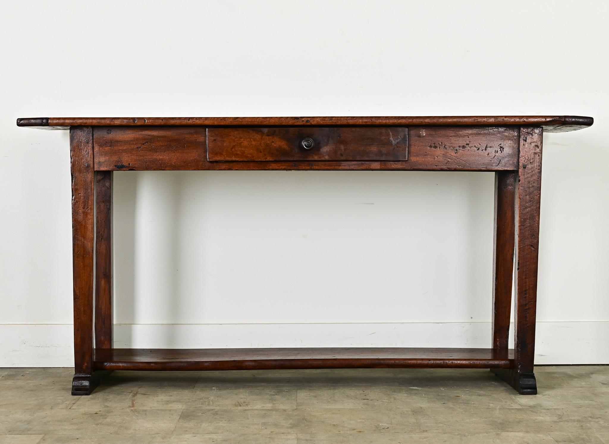 A French country house server, or less formally, a kind of domestic work table, from the 19th century made of solid walnut. The planks of the console surface are curiously more triangular than straight, and framed by breadboard ends. A single,